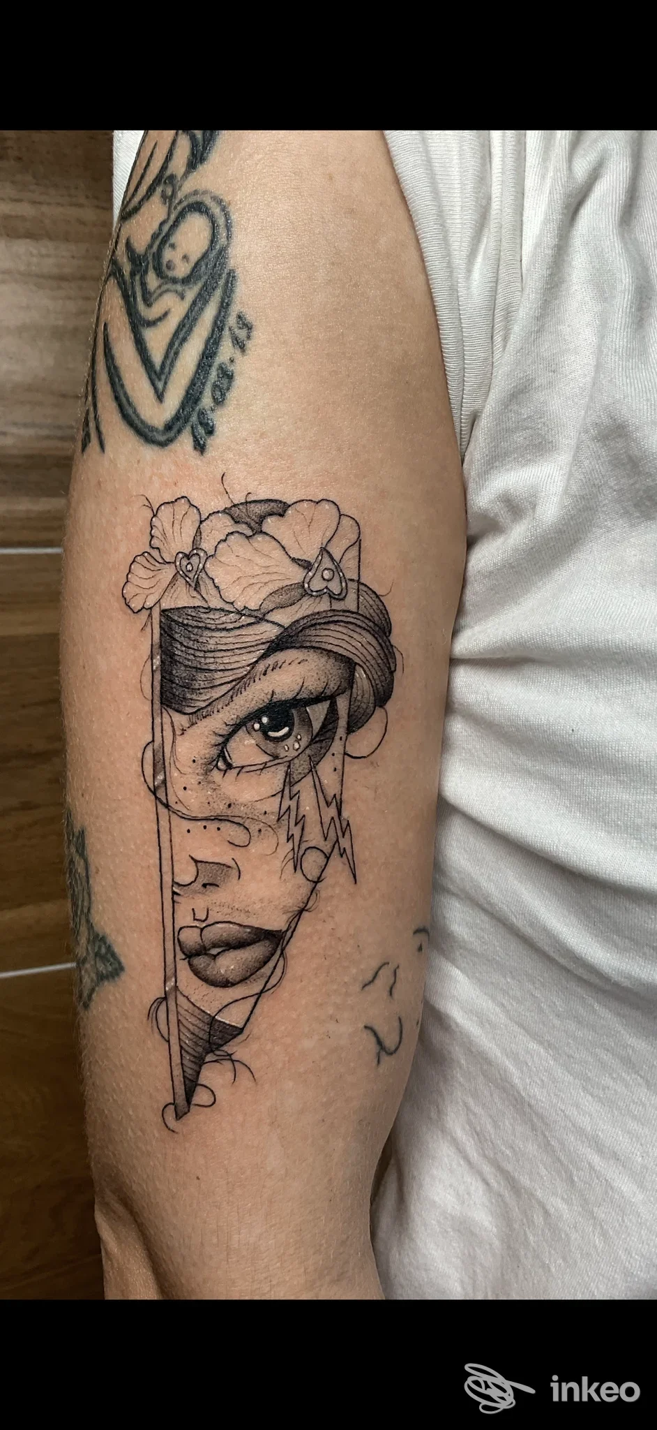 Tatuaggio raffigurante un volto femminile circondato da fiori, eseguito su un braccio; linee nerissime e dettagli realistici, visibile la pelle come supporto del tattoo. Studio Take Your Tattoo, Battipaglia.