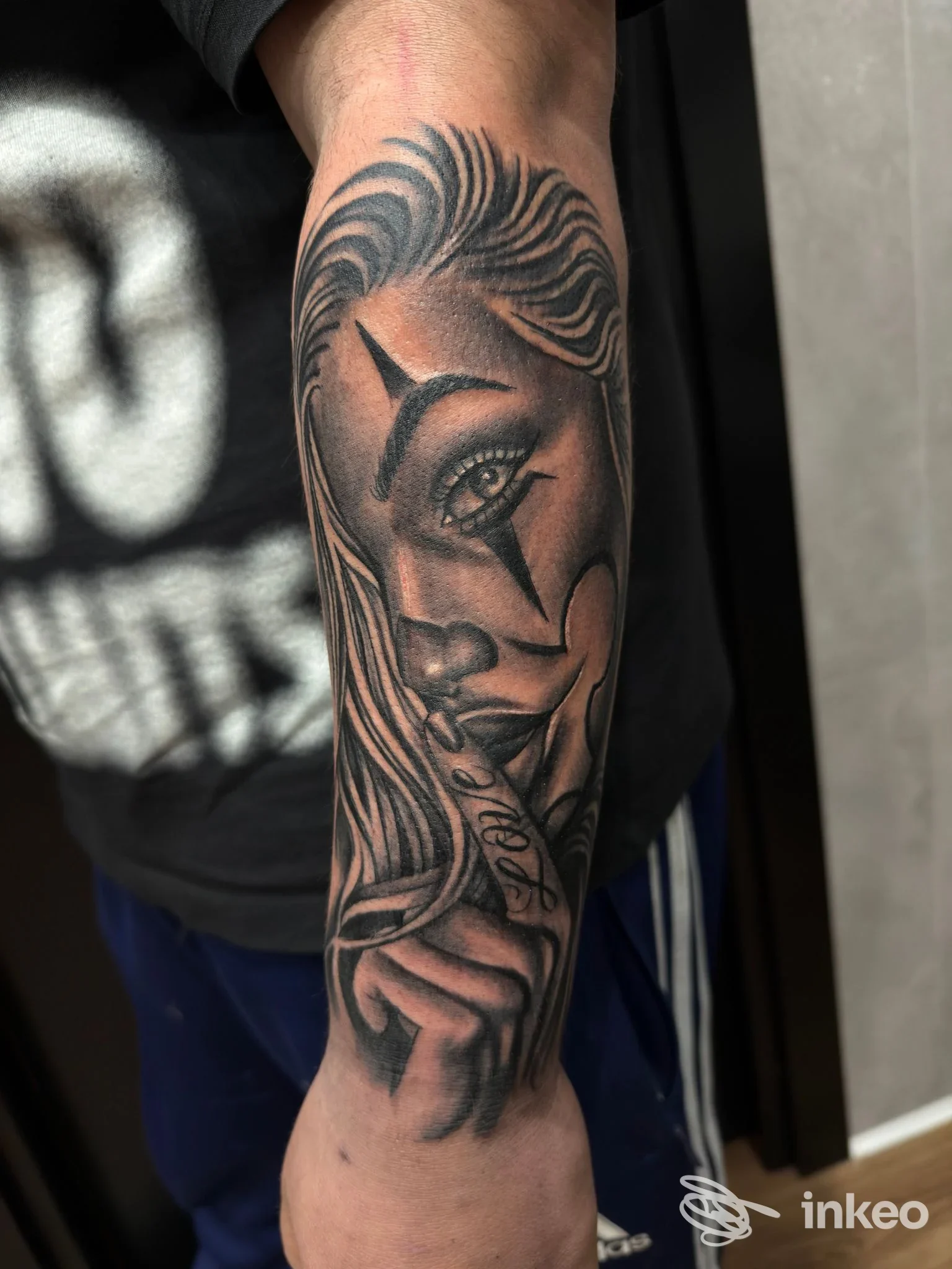 Tattoo visibile sul braccio raffigurante una testa femminile con una stella intorno all'occhio, eseguita in toni scuri su pelle Chiara.
