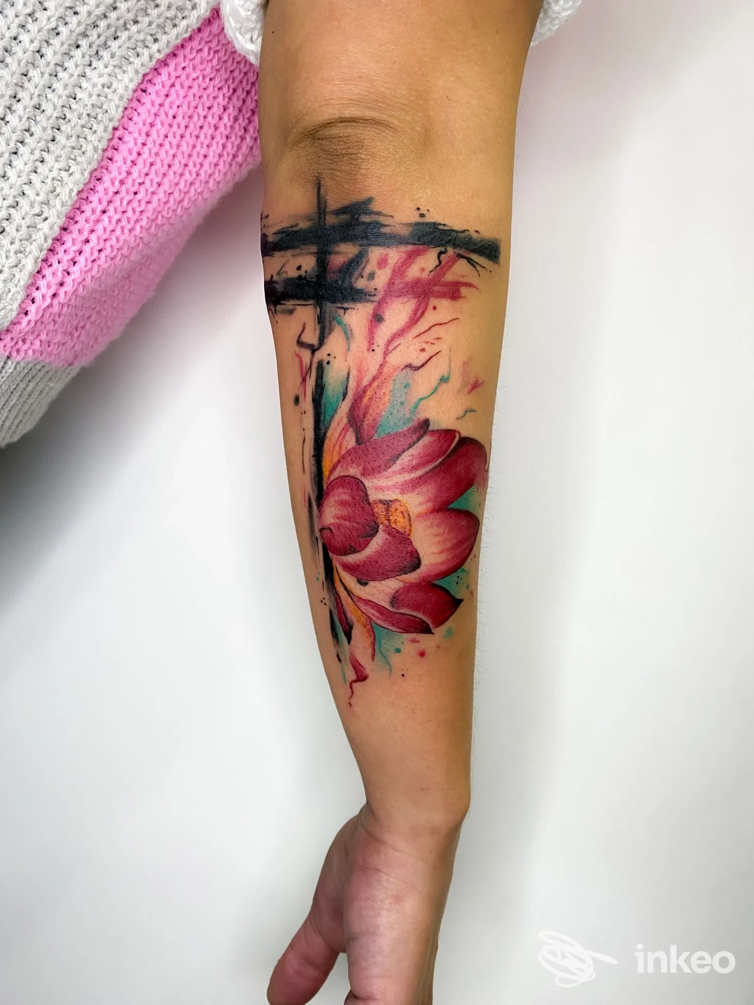 Piercing della pelle sul braccio: tatuaggio floreale colorato con sfondo sfumato e tratti neri; visibile sangue e pennellate stilizzate. studio Antonio Moccia Tattoo Studio, Frattaminore.