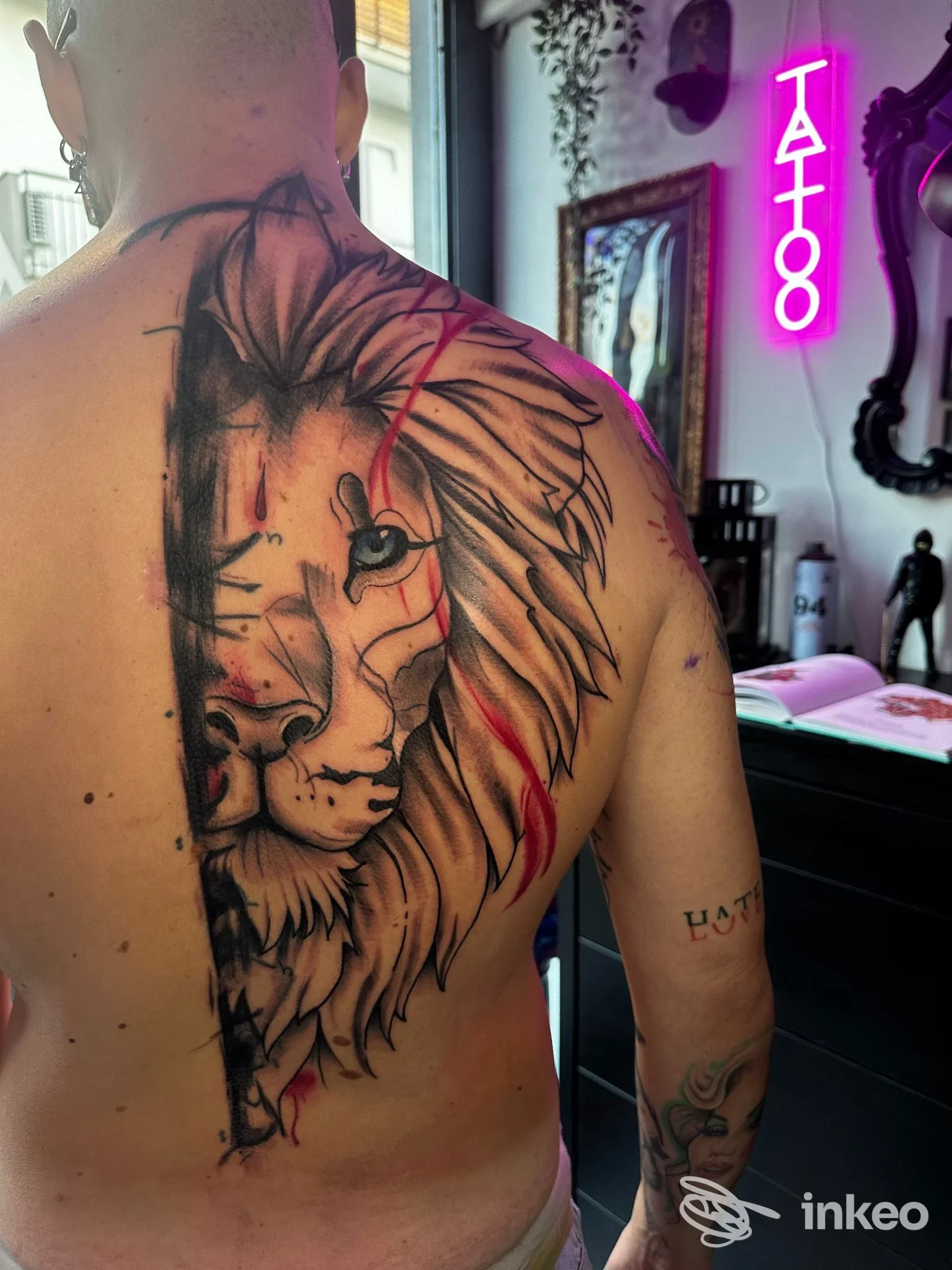 Tattoo realistico sul dorso di un uomo: leone stilizzato con riflessi neri e luci rosa sullo sfondo, studio di Antonio Moccia Tattoo Studio a Frattaminore, inquadratura su spalla e schiena.