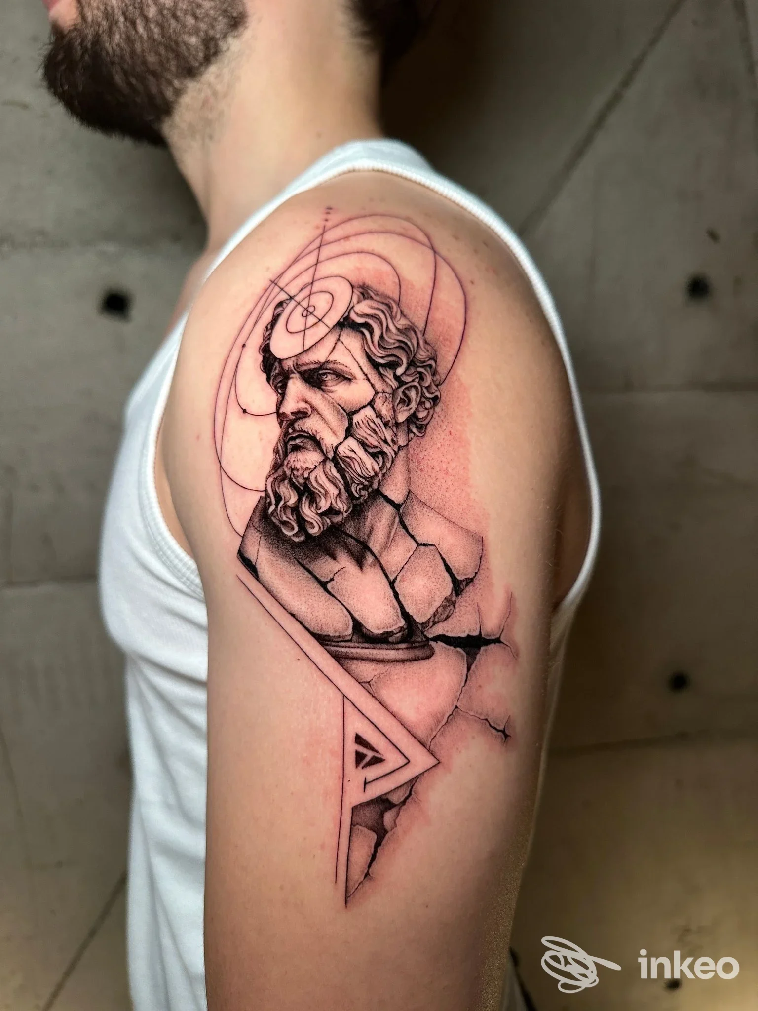 Tattoo sull'avambraccio raffigurante un busto maschile con linee geometriche e contorni neri, senza visione di volto intero.