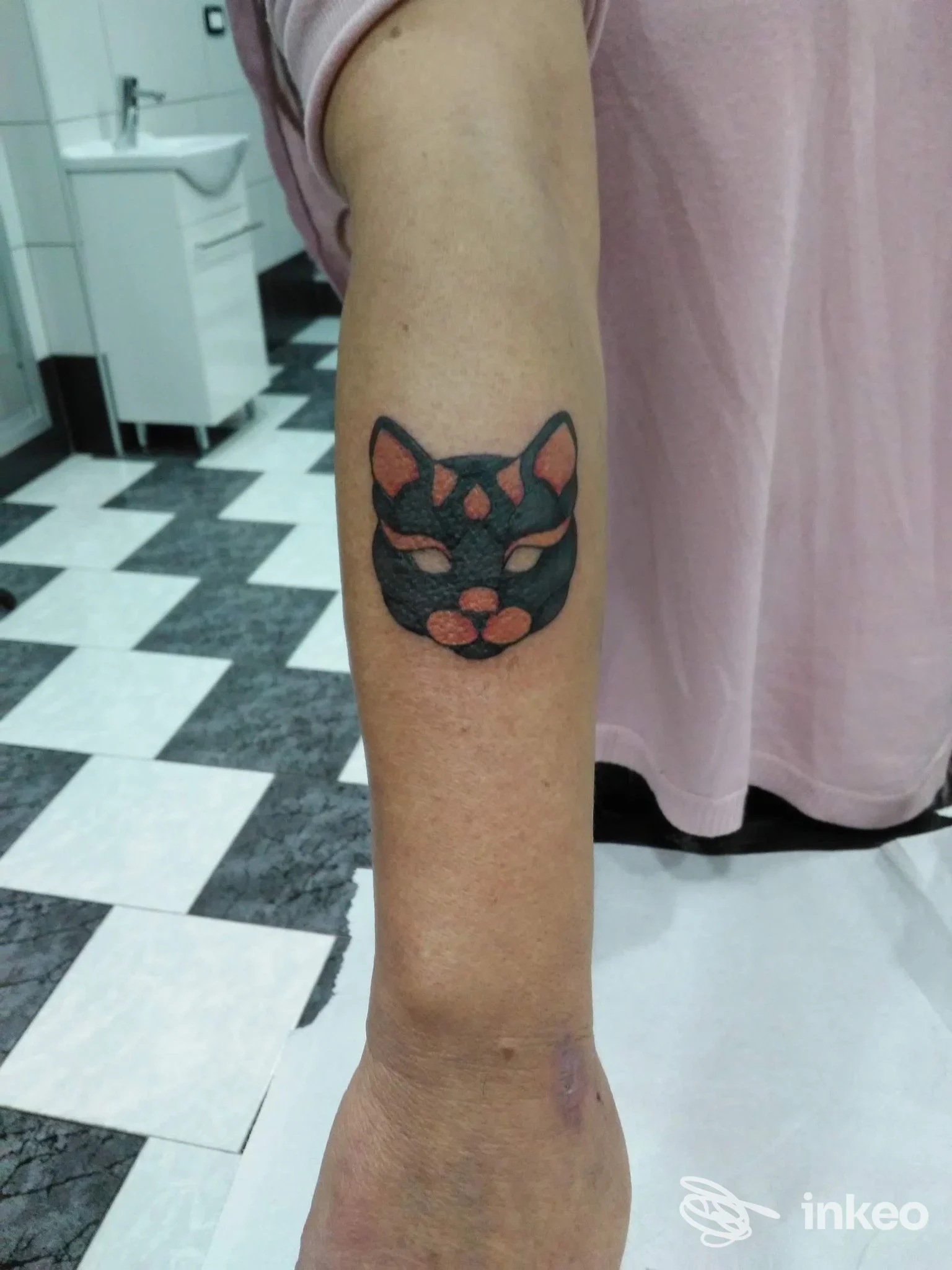 Tatuaggio realistico di un gatto nero stampato sulla pelle del braccio, eseguito presso uno studio; Napoli.