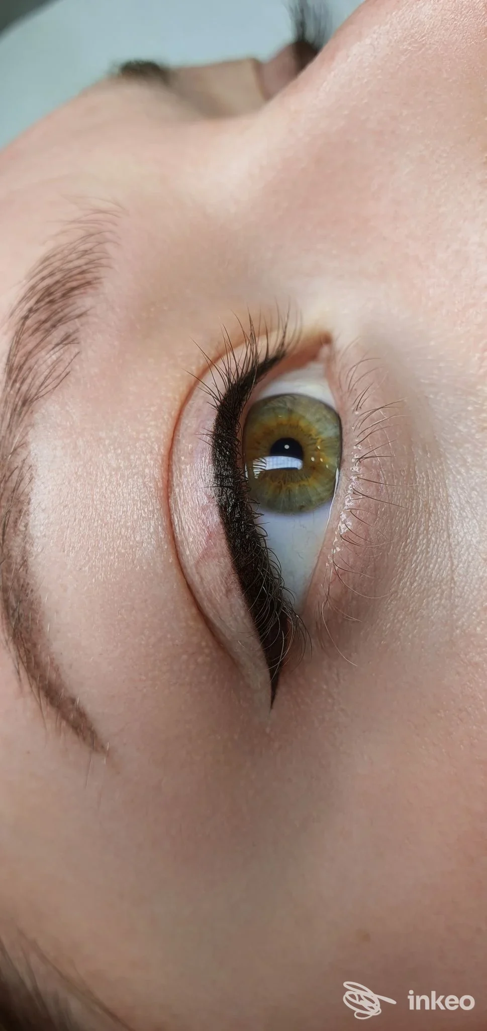 Occhio visto da fianco con pelle illuminata, eyeliner permanente ben definito lungo la linea delle ciglia superiore, senza visione del volto intero.