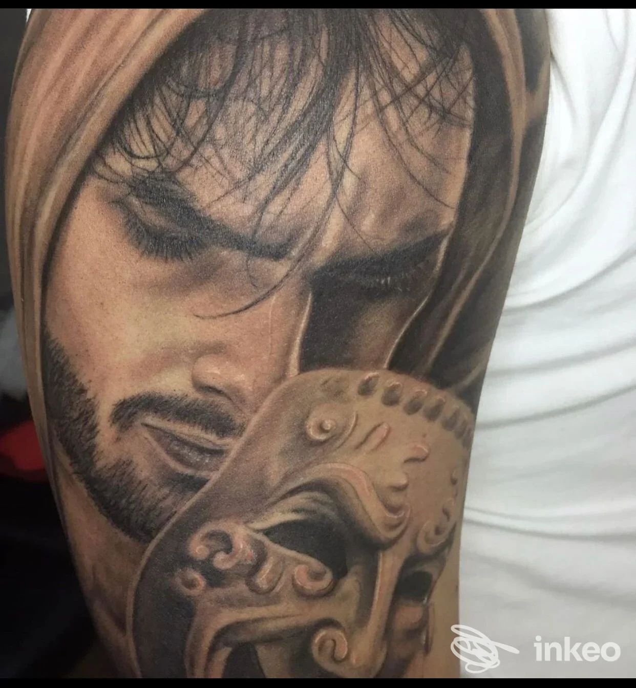 Tatuaggio realistico sul braccio raffigurante una figura maschile, con dettagli di capelli e barba, tonalità nere e grigie su pelle chiara; studio Old River Ink, Aversa.