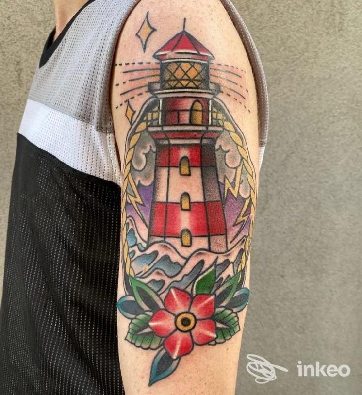 Tatuaggio visibile sul braccio di un faro rosso con onde e fiori rossi e verdi, stile tradizionale, su pelle chiara.