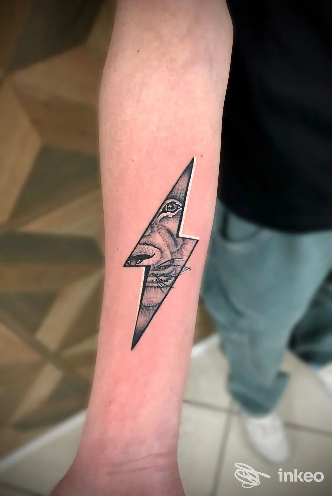 Tatuaggio sul braccio raffigurante una saetta con interno decorato, visibile pelle reale.