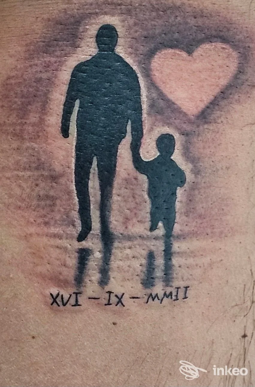 Tattoo visibile su pelle: silhouette di un adulto e di un bambino accanto, con un cuore rosso sullo sfondo.