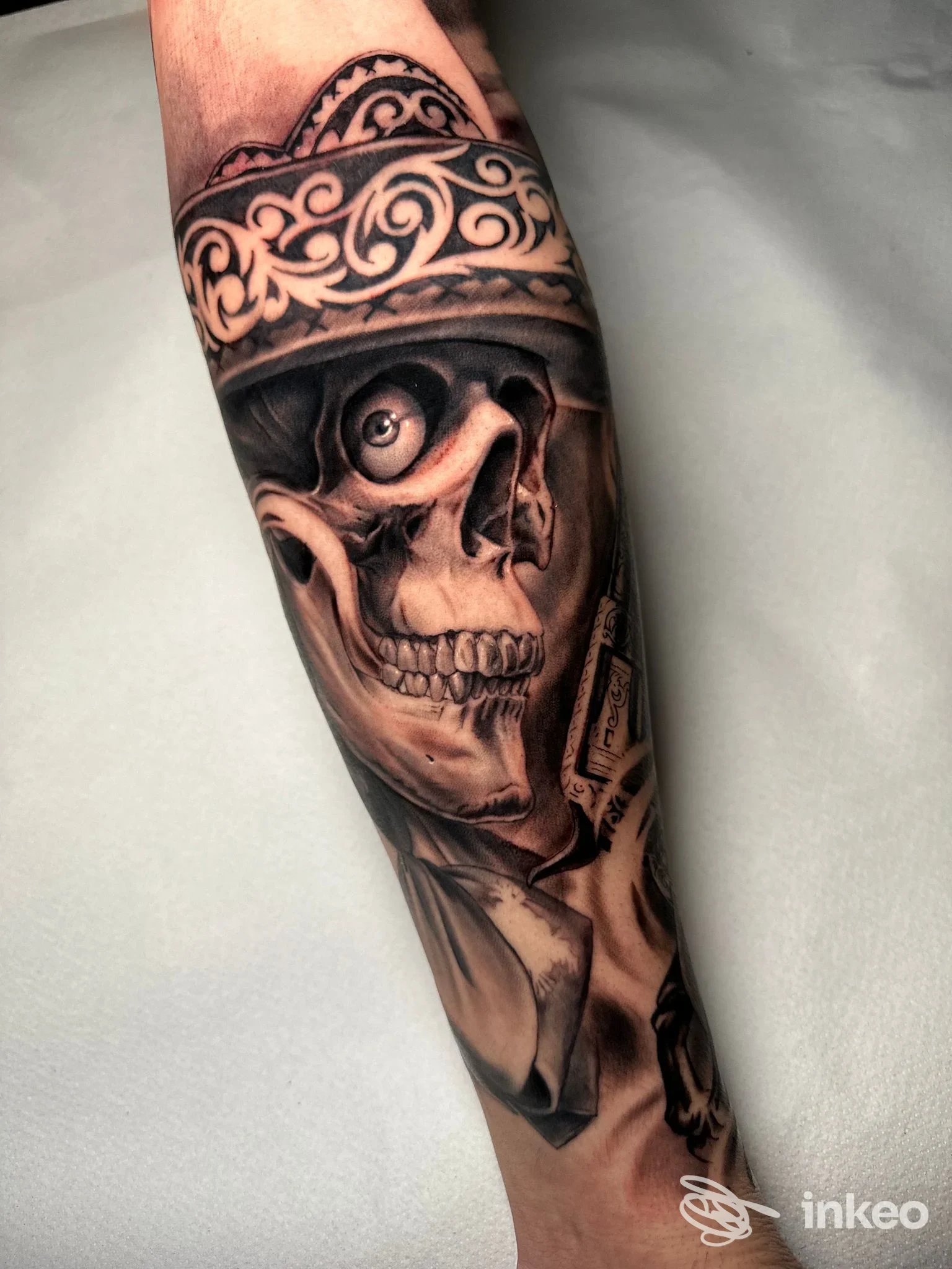 Tatuaggio realistico in bianco e nero su avambraccio: skull con una corona ornamentale, dettagliato e shading marcato, senza volto completo visibile.