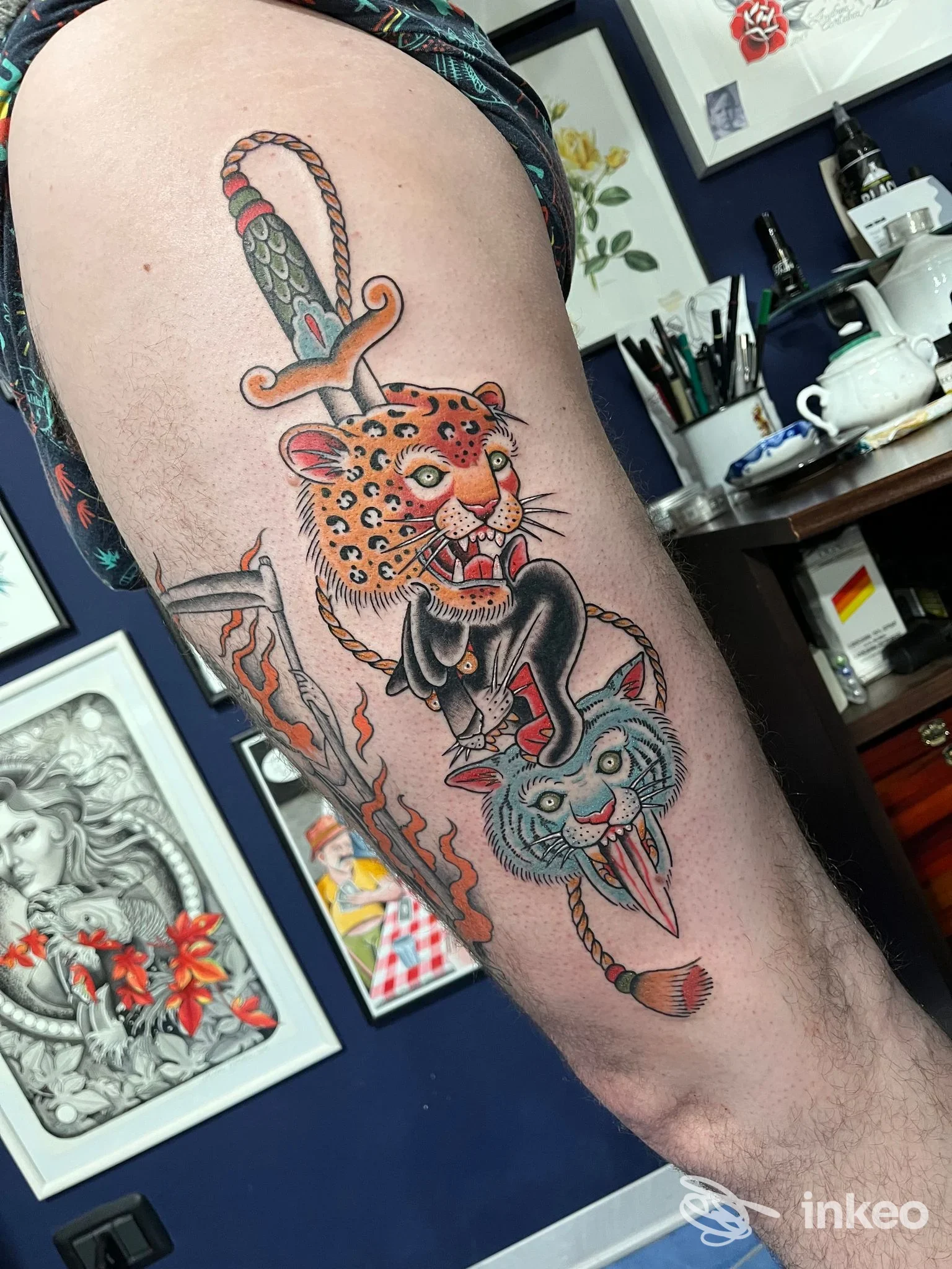 Tattoo a colori su braccio raffigurante un felino tipo tigre e un coniglio azzurro, intrecciati attorno a una corda, visibile in studio tatuaggi.