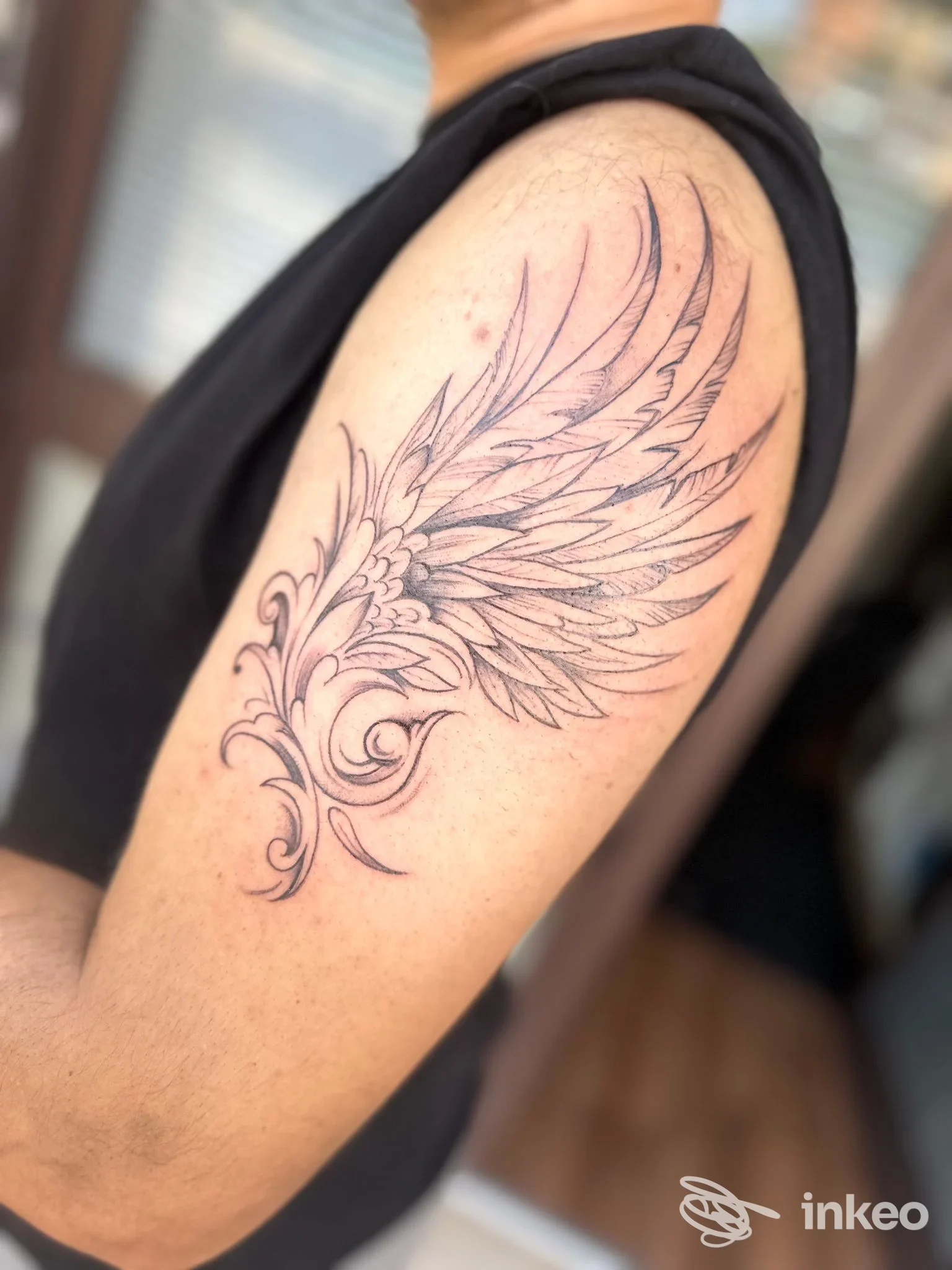 Tatuaggio a ali con motivi floreali lungo la parte superiore del braccio, realizzato da Imprinting Tattoo, Benevento.