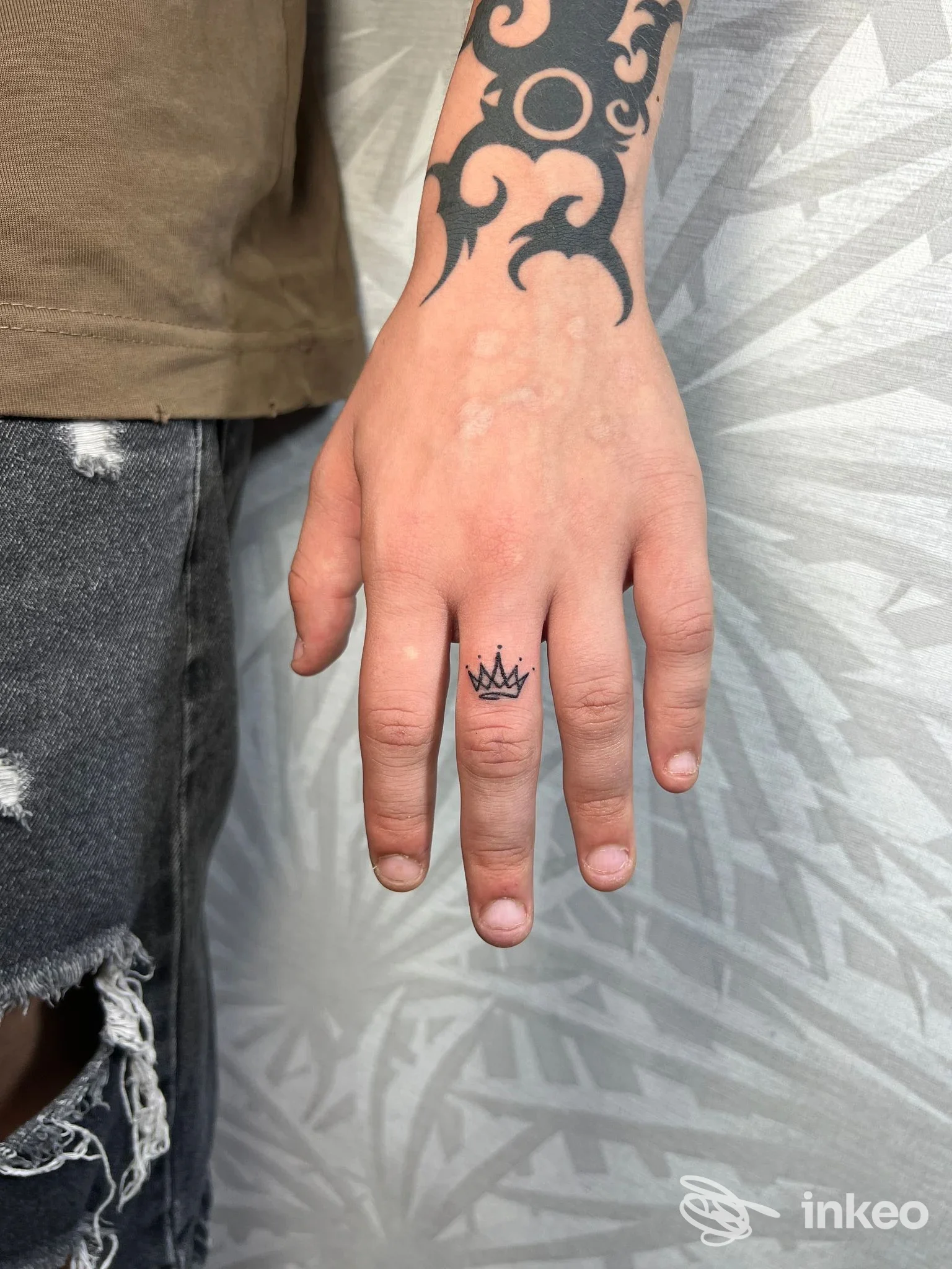 Tatuaggio sul dito: piccola corona nera disegnata sulla falange della mano, visibile e chiara, studio Naps Studio Tattoo & Piercing a Pompei.
