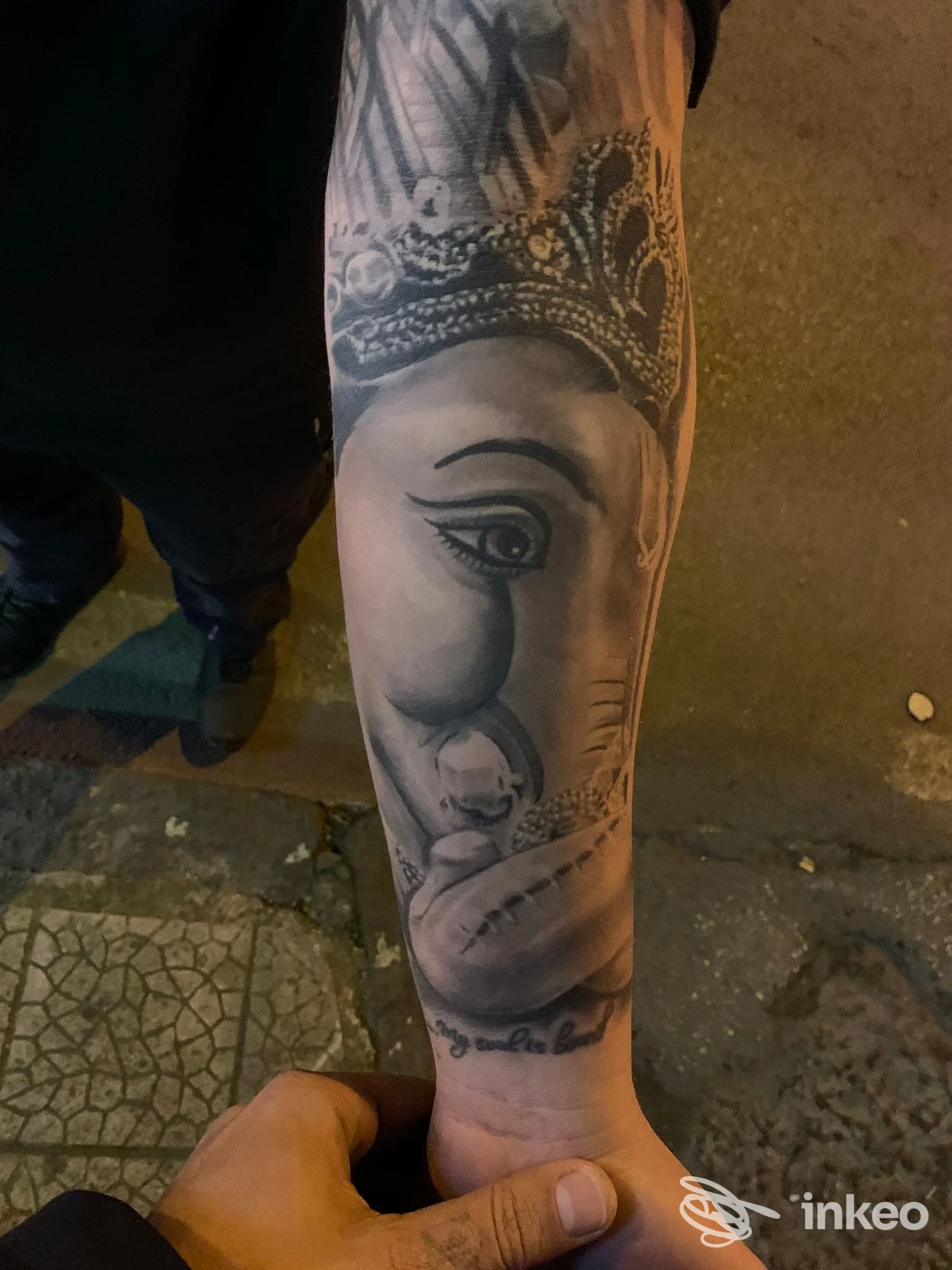 Tattoo realistico su avambraccio raffigurante una figura femminile con corona; colori in tonalità grigie e nere, eseguito direttamente sulla pelle.