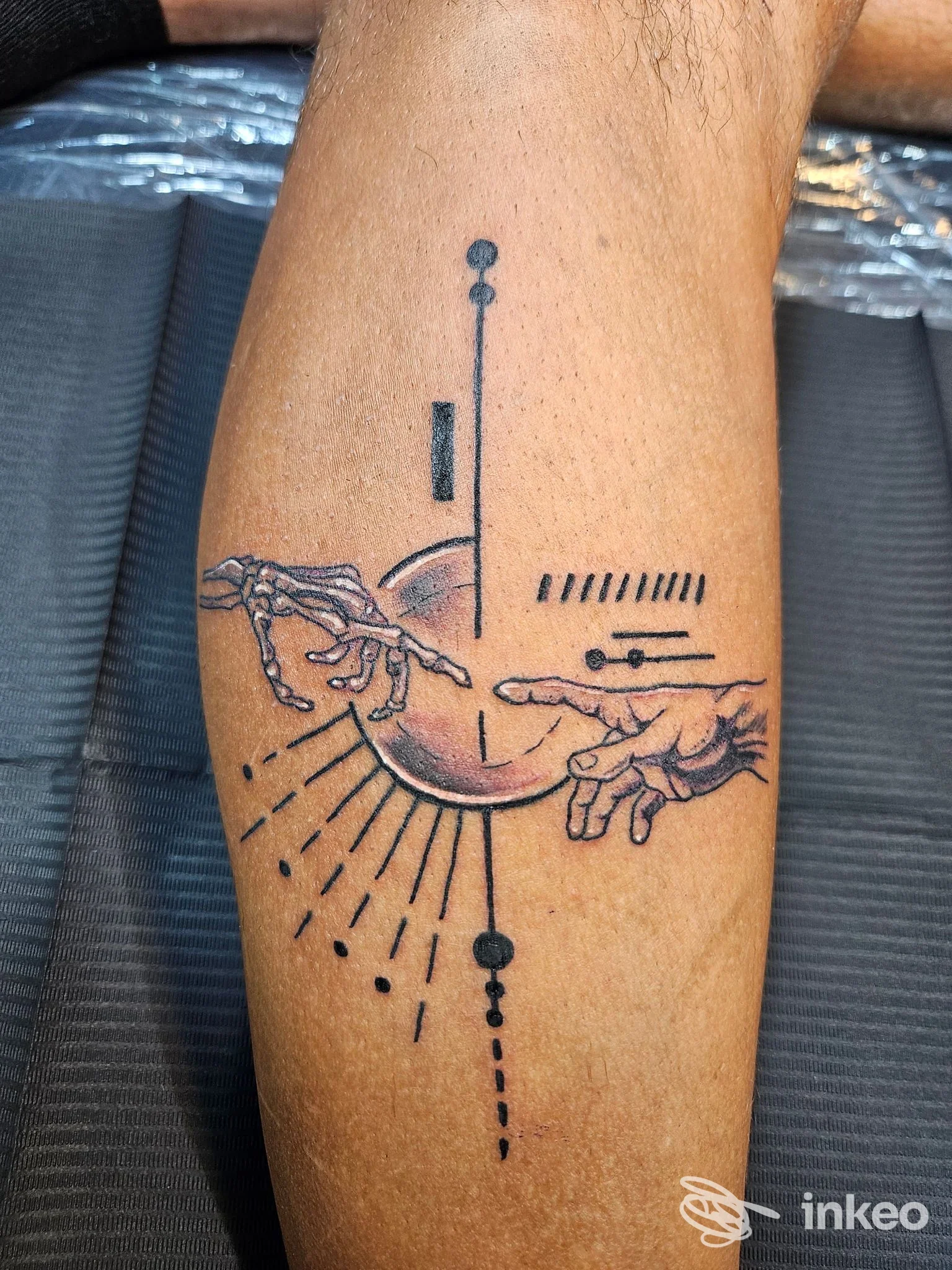 Tatuaggio geometrico con mani che sostengono una sfera, su pelle della gamba; stile lineare nero, realizzato da Ramificazioni Tattoo Caserta