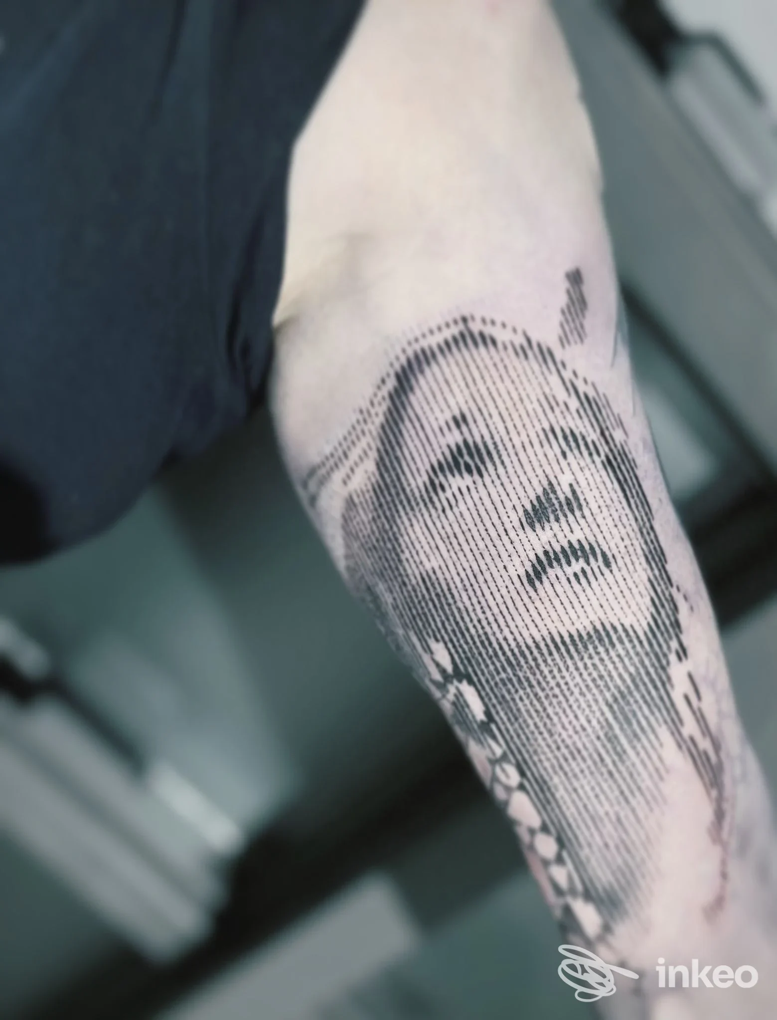 Un braccio nudo mostra un grande tatuaggio in stile mezzotinta di una figura femminile, senza elementi di social media o testo promozionale visibili.