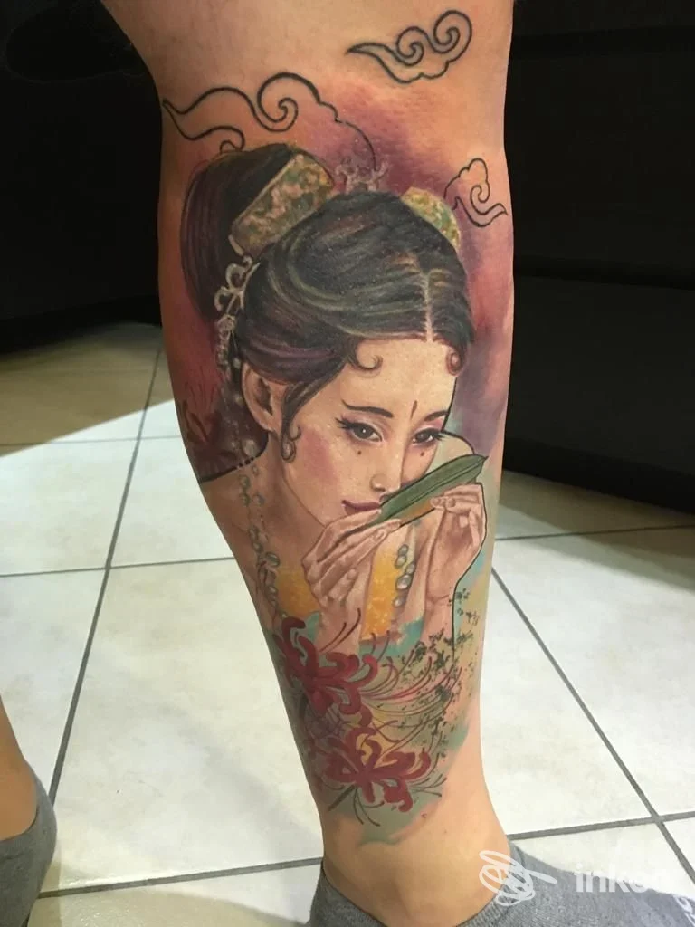 Tatuaggio realistico sul polpaccio raffigurante una giovane donna giapponese che tiene un ventaglio, con colori vividi e dettagli floreali; studio Sweet Dama Tattoo, Battipaglia.