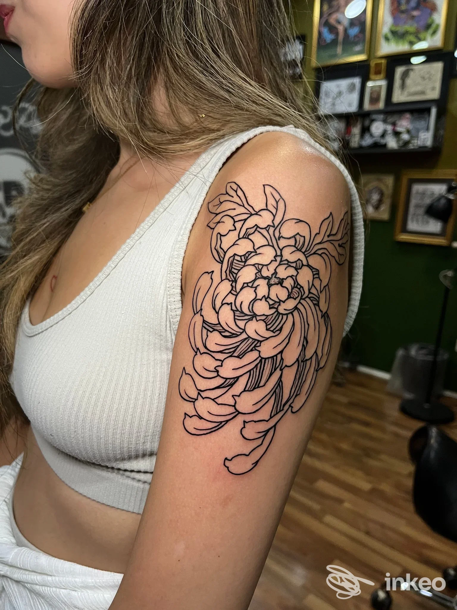Tattoo floreale stilizzato sull'avambraccio di una persona, visibile di profilo, linee nere su pelle chiara, sfondo di studio Tattoo Point Studio a Napoli.