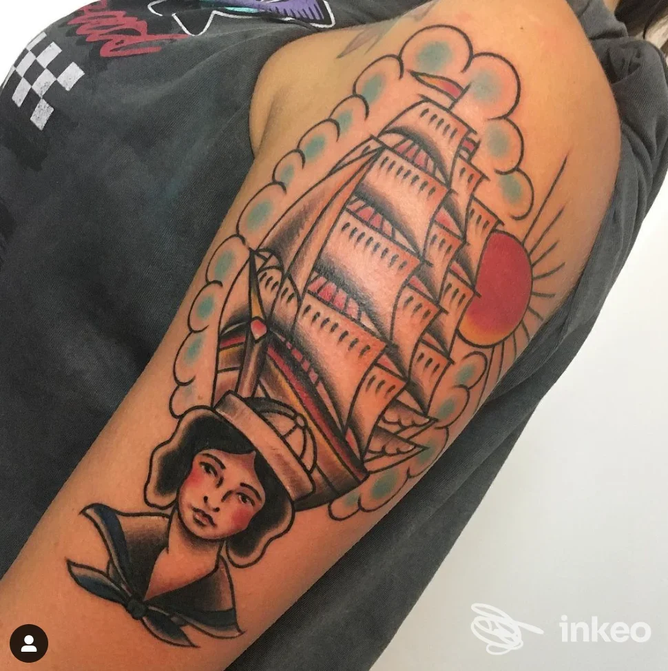 Tattoo a braccio raffigurante una vela di una nave e un volto femminile, con sole rosso sullo sfondo, stile tradizionale, braccio di una persona.