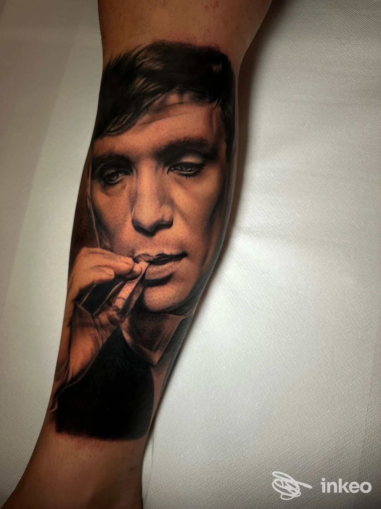Tattoo realistico sul braccio raffigurante una persona che fuma, eseguito da Tinta Santa Tattoo Studio a Succivo, tonalità scure e dettagli realistici.