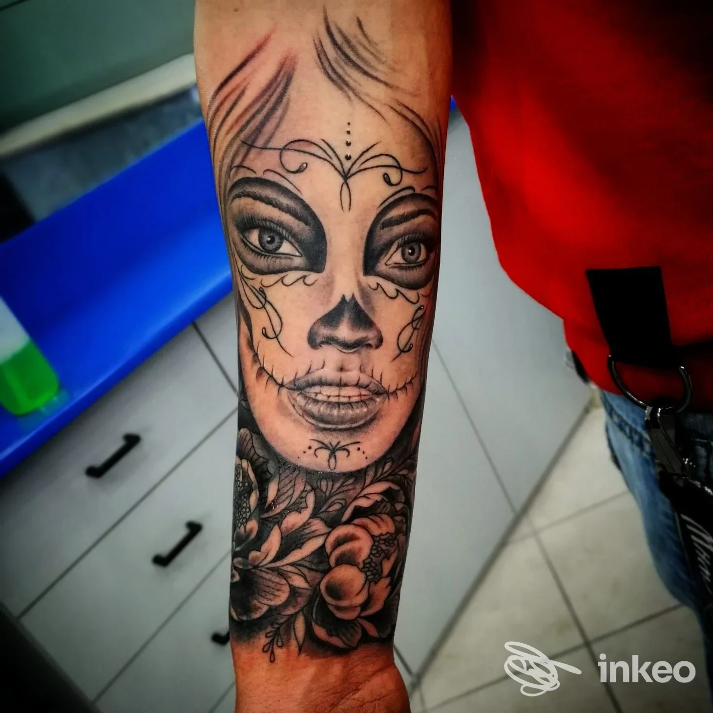 Tattoo sul braccio raffigurante una testa femminile in stile sugar skull, con motivi decorativi e fiori, eseguito su pelle reale.