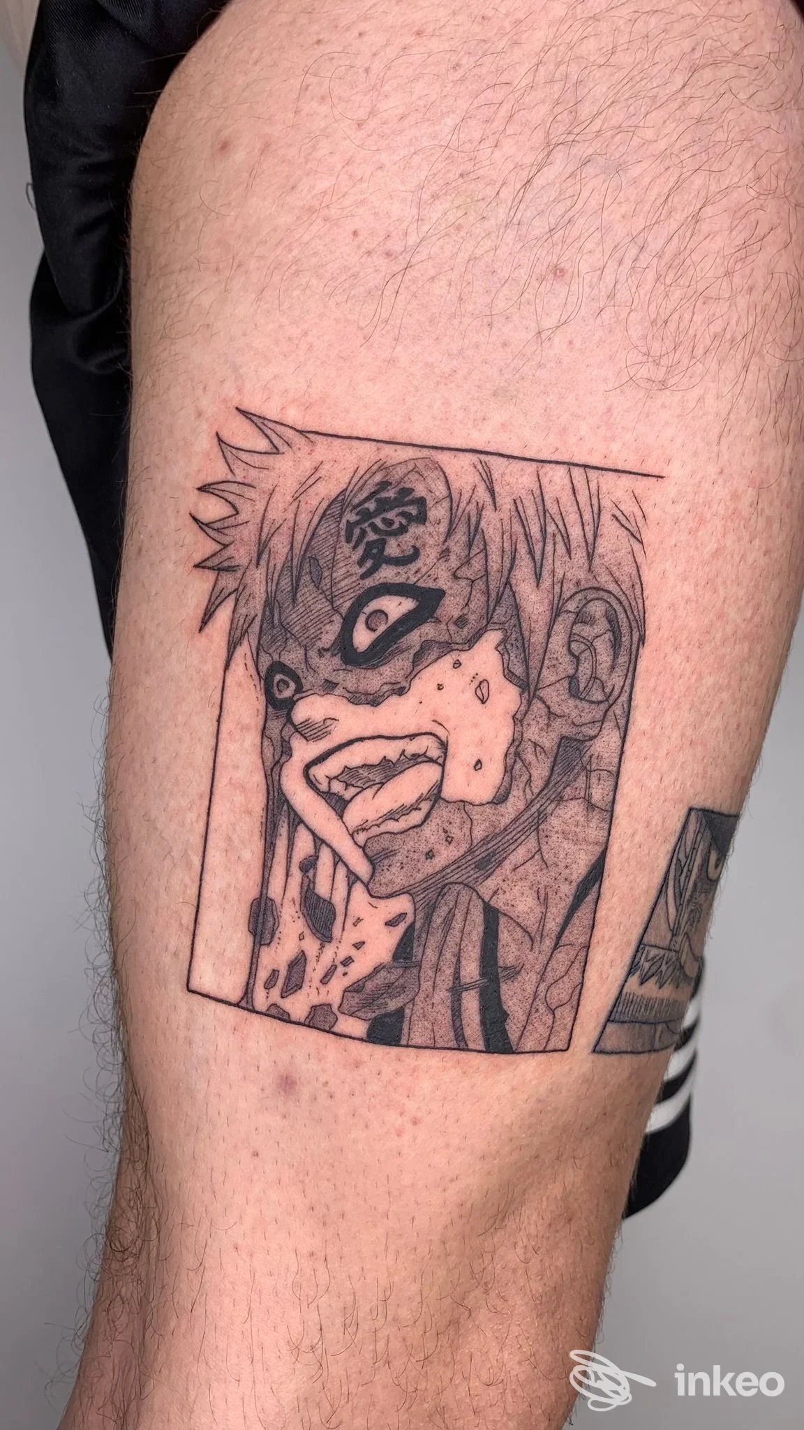 Tattoo in stile manga visibile sulla pelle della gamba, ritratto angolare di un personaggio in bianco e nero racchiuso in un rettangolo.
