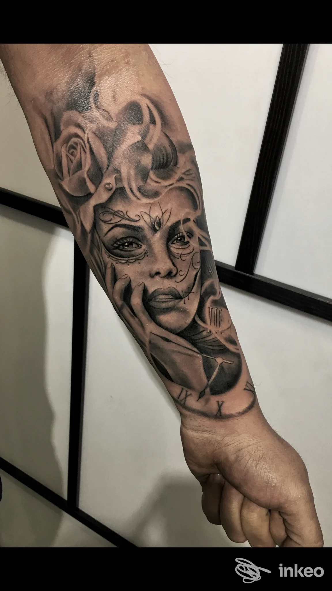 Tattoo realistico sul braccio raffigurante una figura femminile con rose, realizzato sulla pelle, bianco e nero con sfumature grigie.