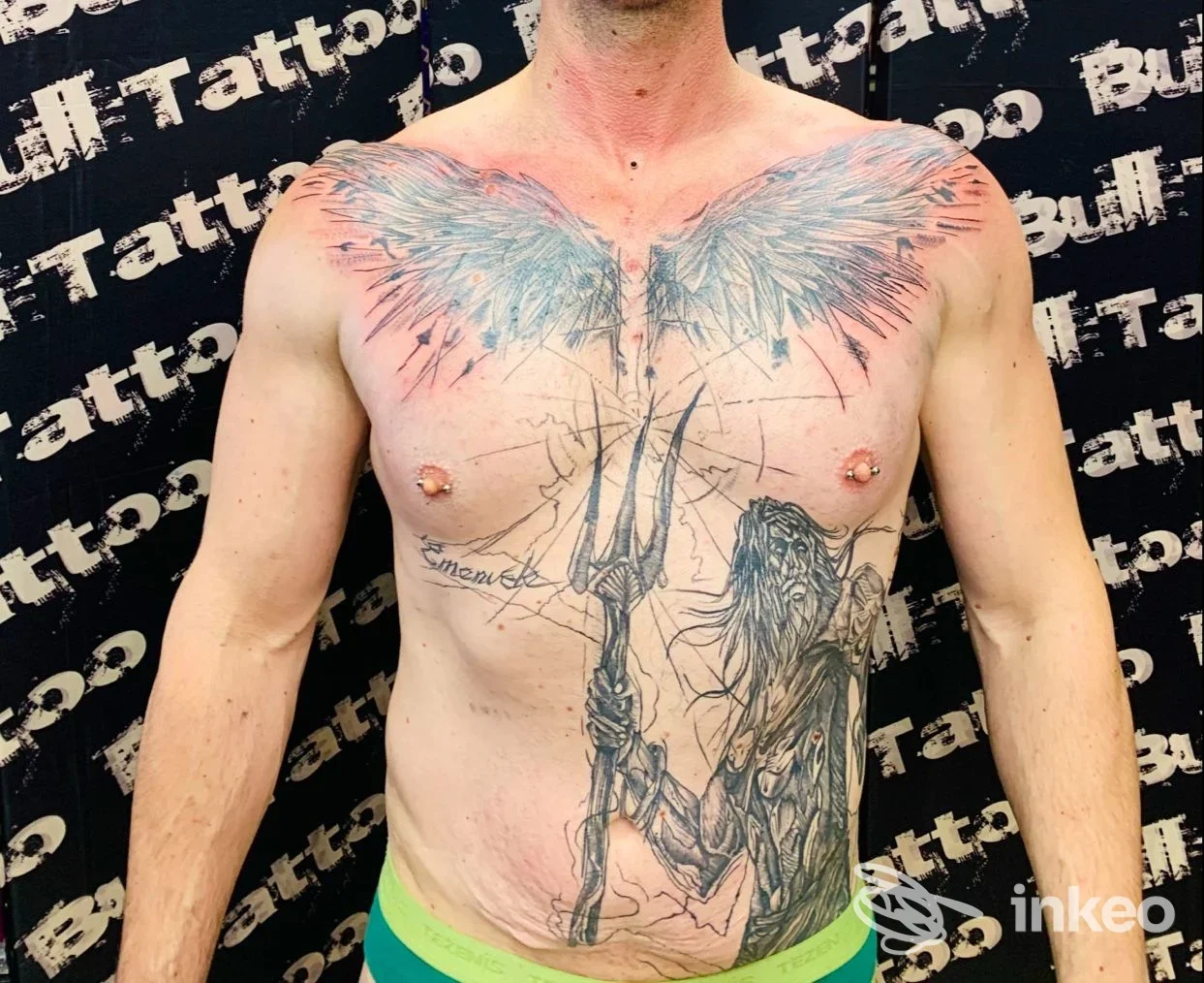 Torace di un uomo nudo con grande tatuaggio di ali azzurrine sul petto e figura stilizzata sottostante, sfondo con logo Bull Tattoo Napoli.