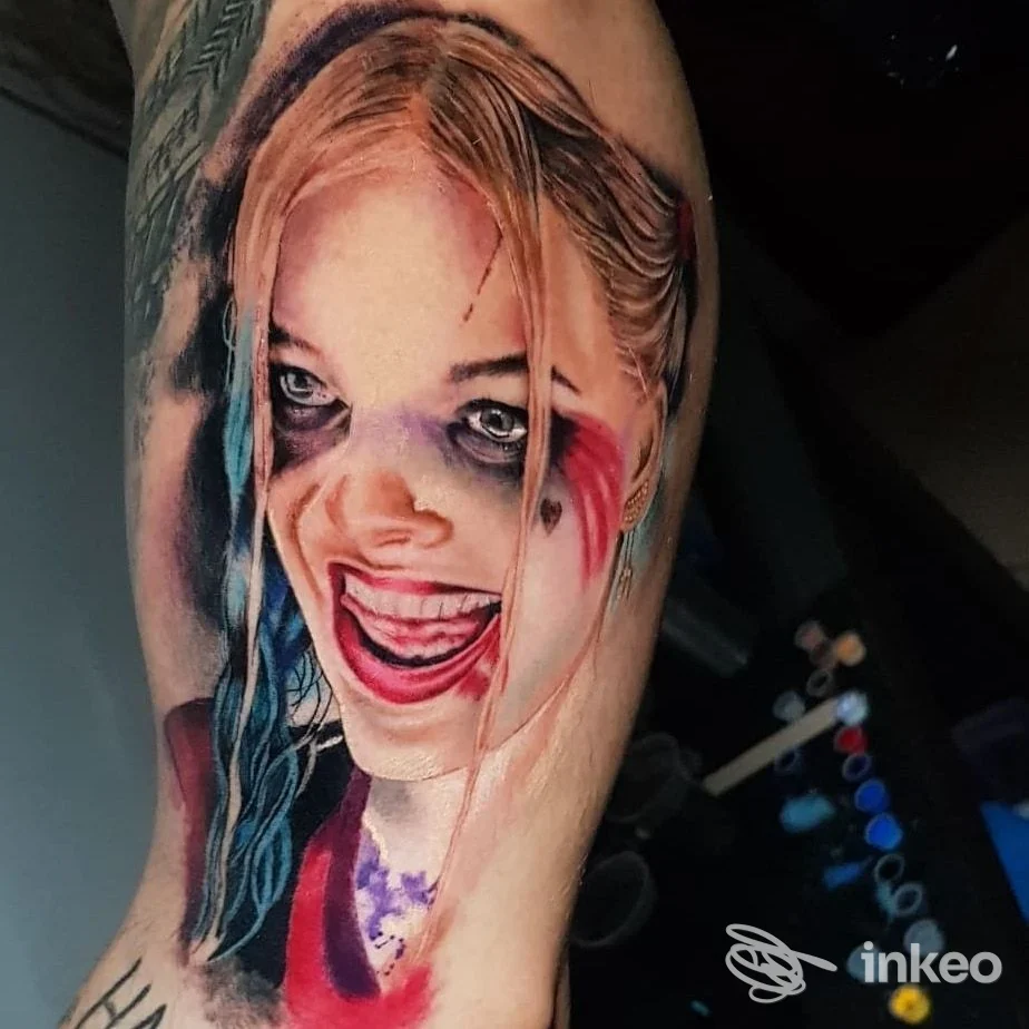 Tattoo realistica di una figura femminile, colori vividi e dettagli nitidi su pelle, viso stilizzato con capelli bianchi e rosso/blu su un braccio.