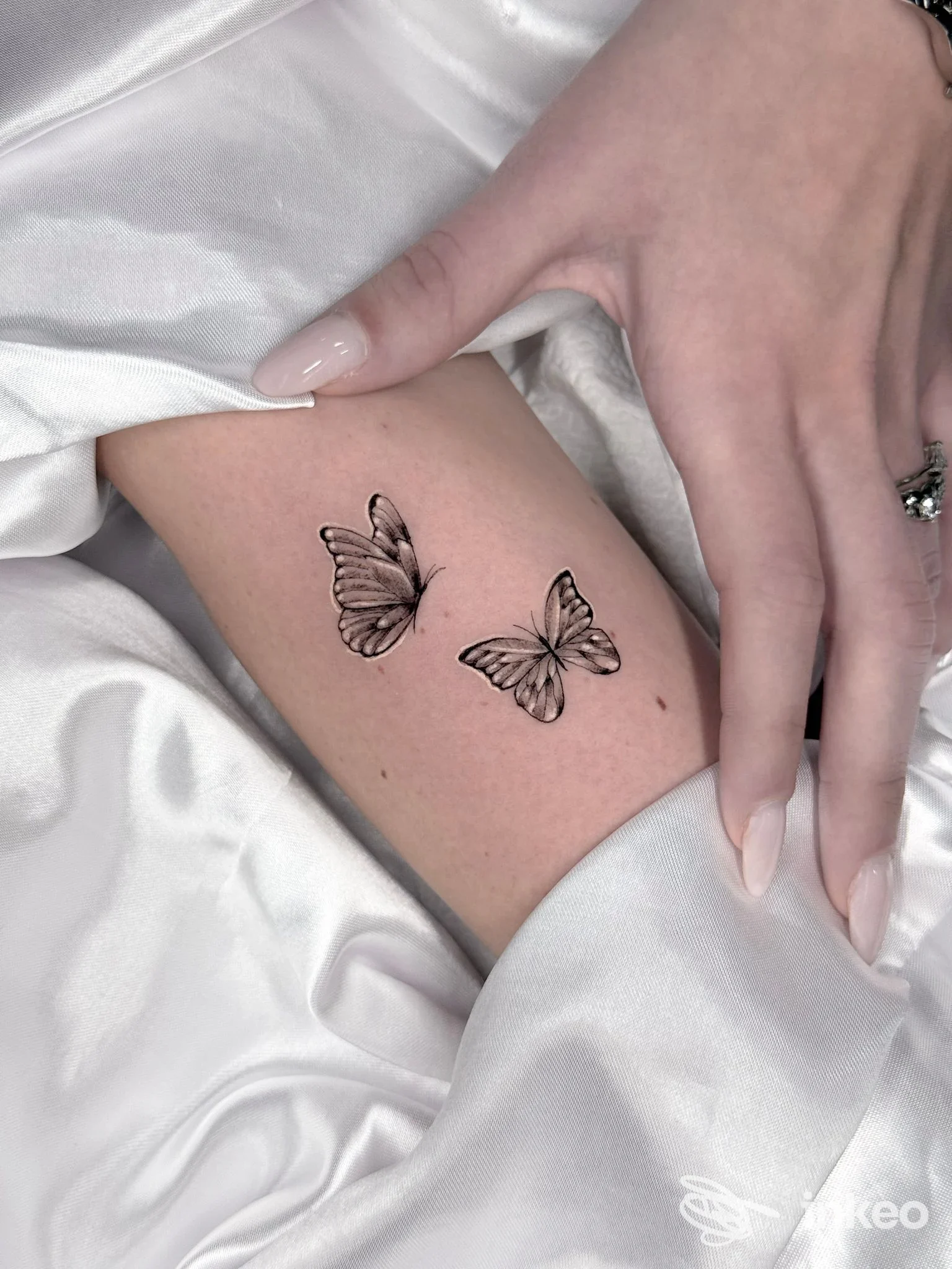 Due farfalle in nero tatuate sulla pelle, posizionate sul polso, realizzate su pelle; tatuaggio eseguito nello studio PFT Studio a Napoli.