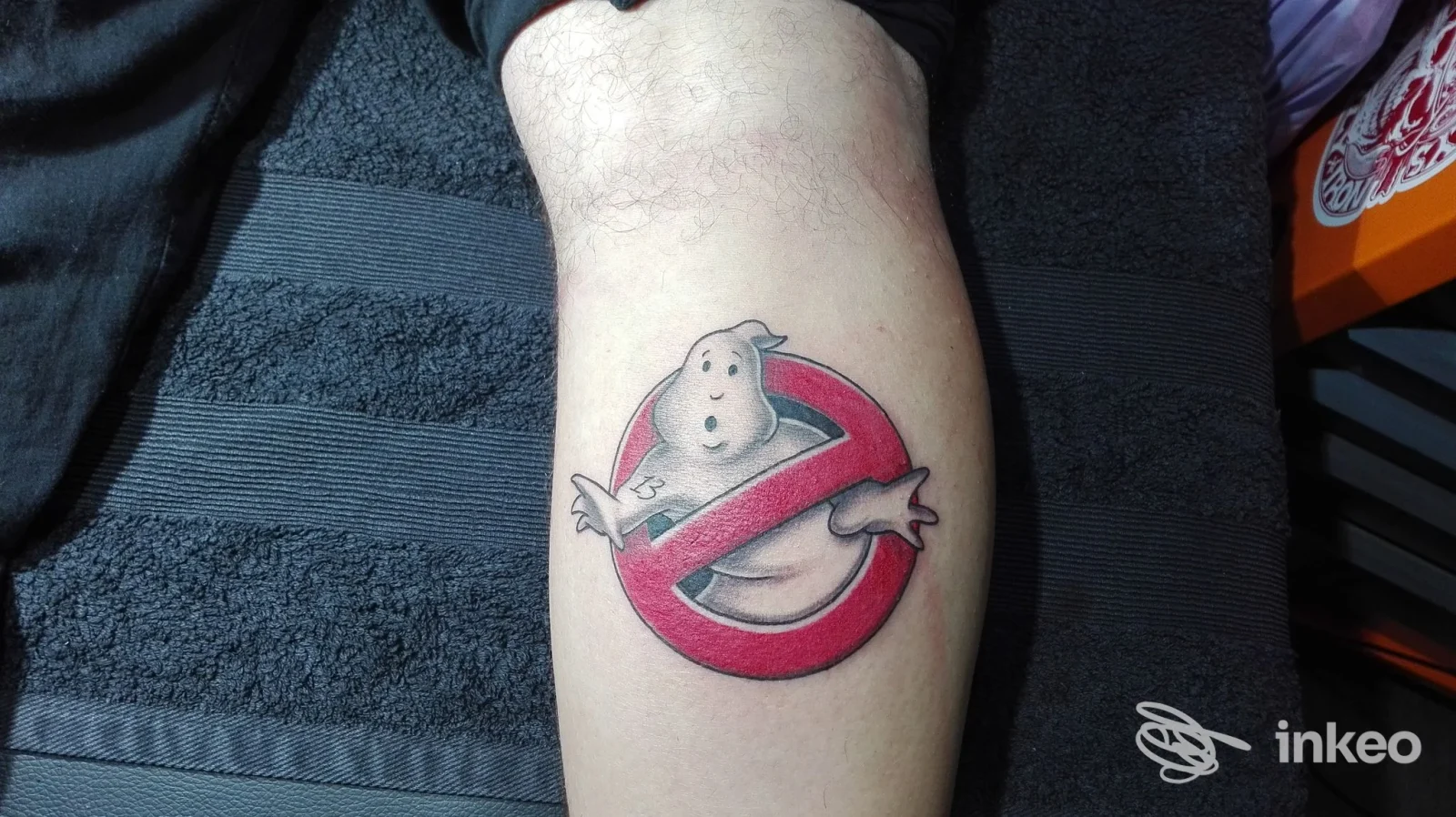 Tattoo stile Ghostbusters sul braccio, logo iconico rosso e bianco, realizzato direttamente sulla pelle.