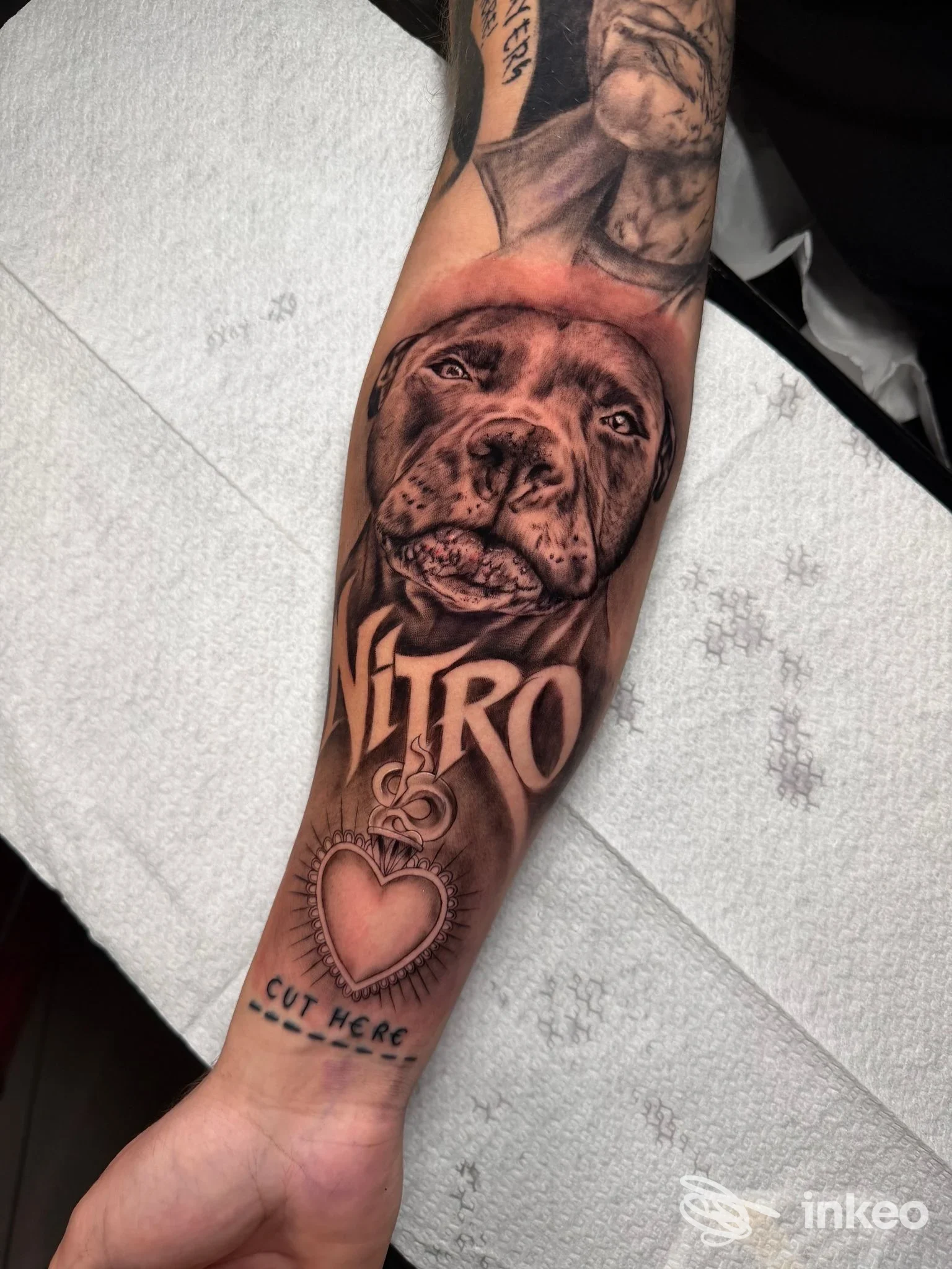 Tattoo realistico su avambraccio raffigurante un cane, con testo Nitro e pendente a cuore, realizzato nello Shameless Tattoo Studio a Lioni, Italia.
