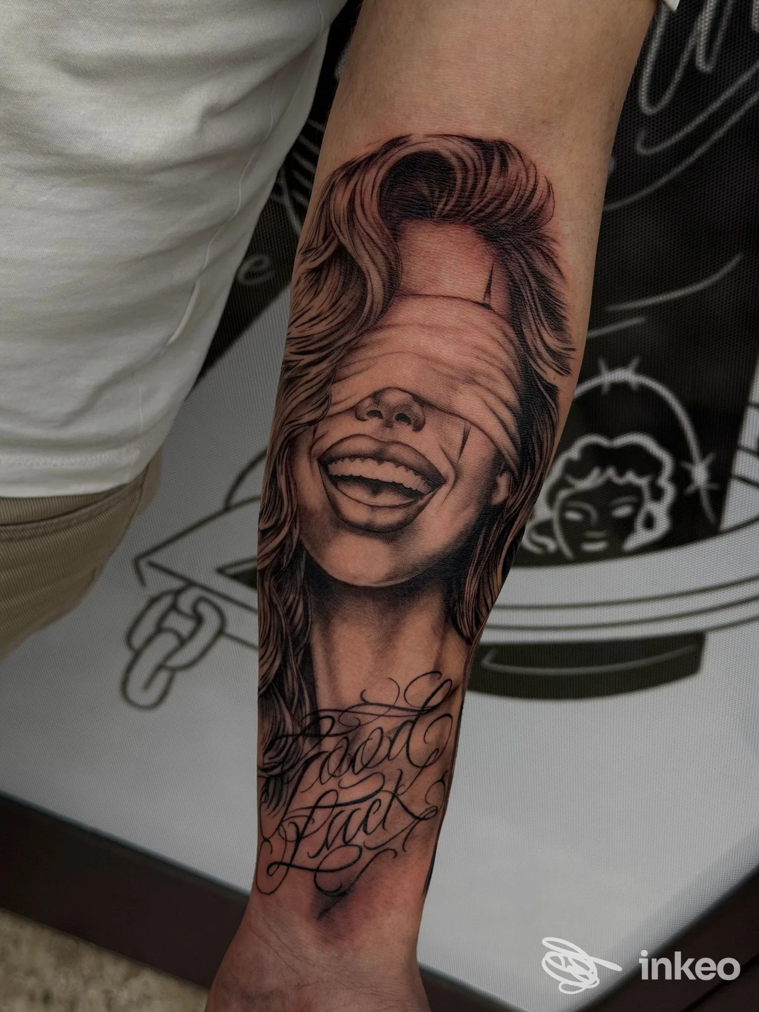 Tattoo realistico sull’avambraccio: ritratto in bianco e nero di una persona che ride, con scritta decorativa sotto. studio Shameless Tattoo Studio, Lioni (Italia).