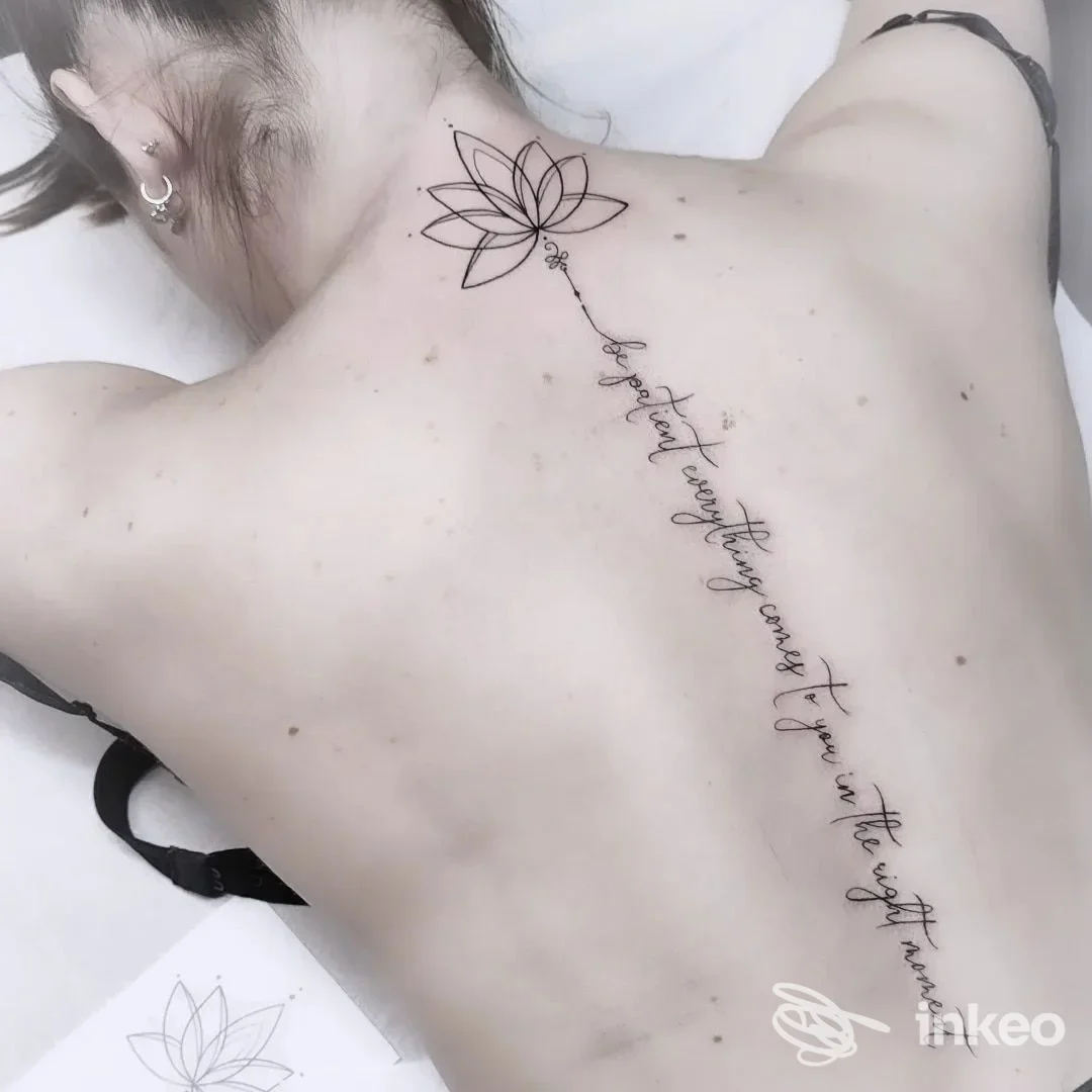 Tattoo sulla schiena con una linea di testo in corsivo che sale lungo la colonna vertebrale, accompagnato da un motivo di loto vicino al collo, eseguito da Old Skull Tattoo Lab a Fisciano.