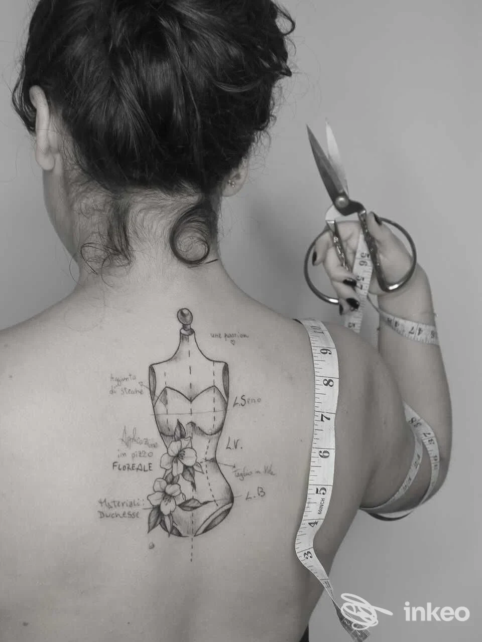 Tattoo visibile sulla schiena di una persona: bozzetto anatomico con fiori su pelle, con forbici e metro in primo piano; studio Etherea Tattoo, Caserta.