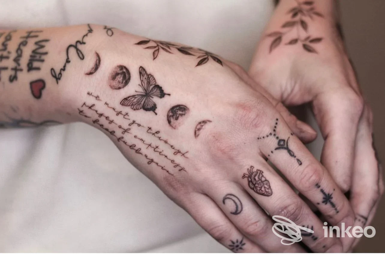 Mani con tatuaggi visibili su pelle: linee sottili e motivi di farfalle, luna e stelle sul dorso della mano, studio Etherea Tattoo Caserta.