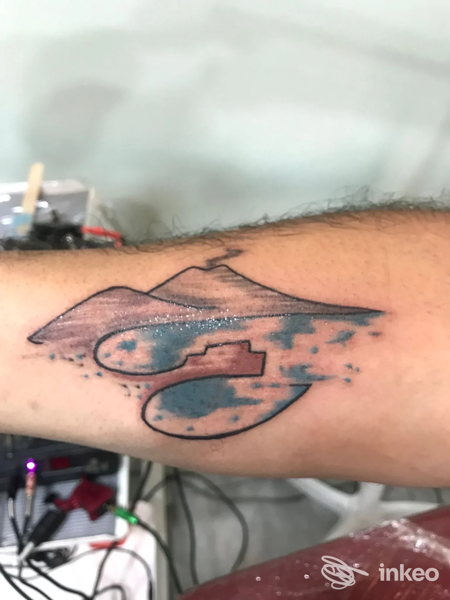 Tatuaggio sul braccio raffigurante montagne e cieli blu scuro, realizzato presso uno studio Tattoo Parlor a Napoli, visibile chiaramente sulla pelle.