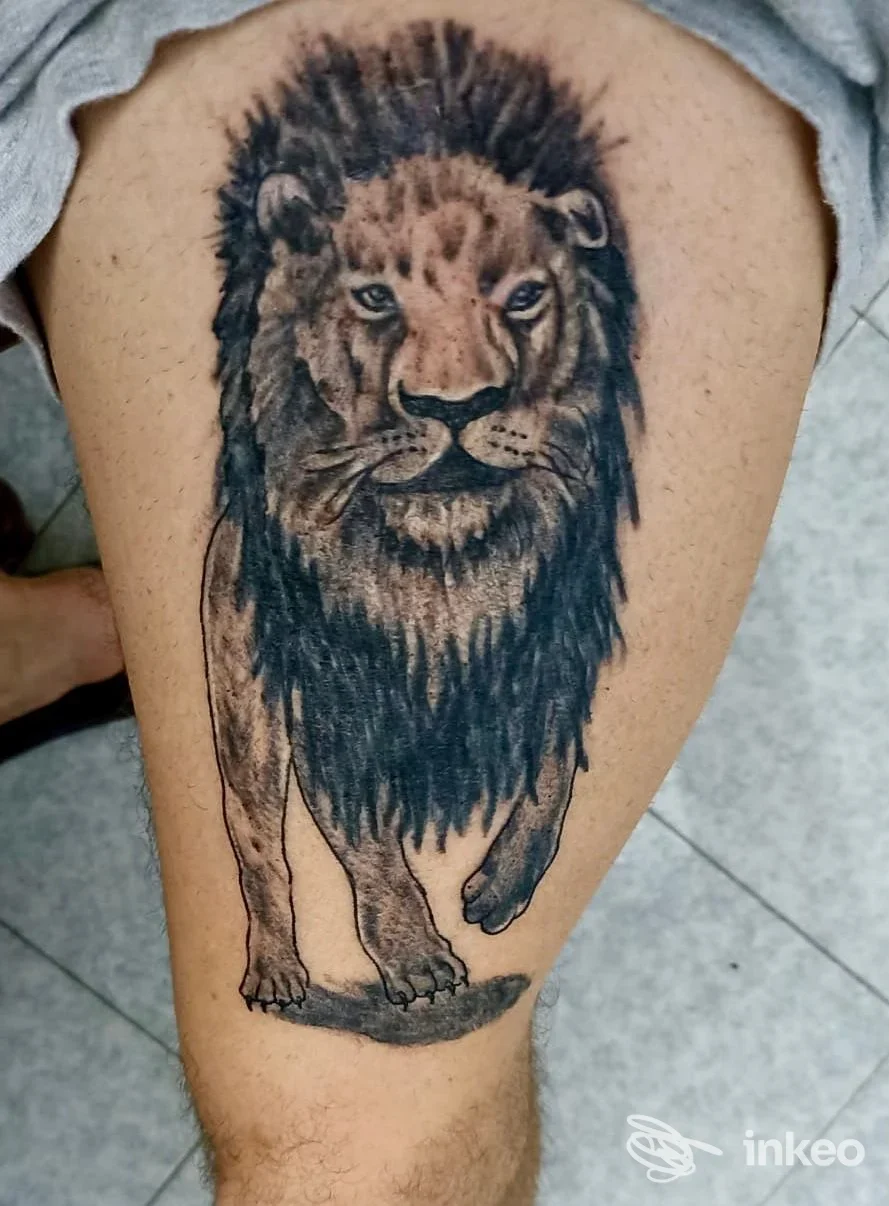 Tattoo realistico di un leone sulla coscia, tonalità grigie, visibile chiaramente sulla pelle.