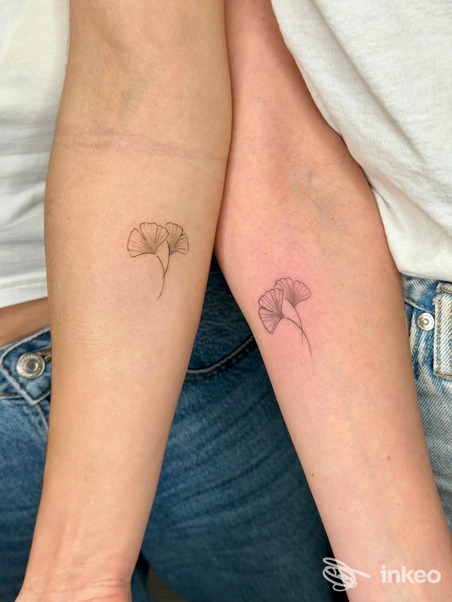 Due avambracci visibili mostrano due piccoli tatuaggi di foglie stilizzate, linea sottile, realizzati direttamente sulla pelle, scatto ravvicinato.