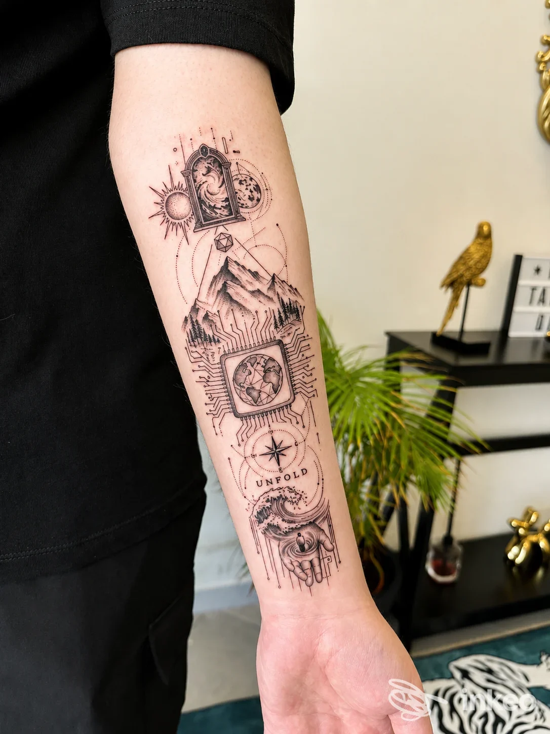 Tattoo sul braccio sinistro, disegno composito con figure geometriche e simboli, realizzato in nero, visibile in primo piano.