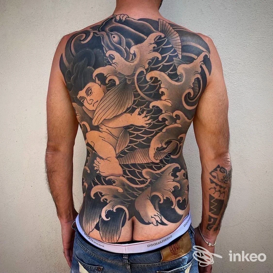 Tattoo integrale sulla schiena di un uomo, stile giapponese con dragoni e nuvole nere e grigie, visibile fino ai fianchi. non si vede volto.