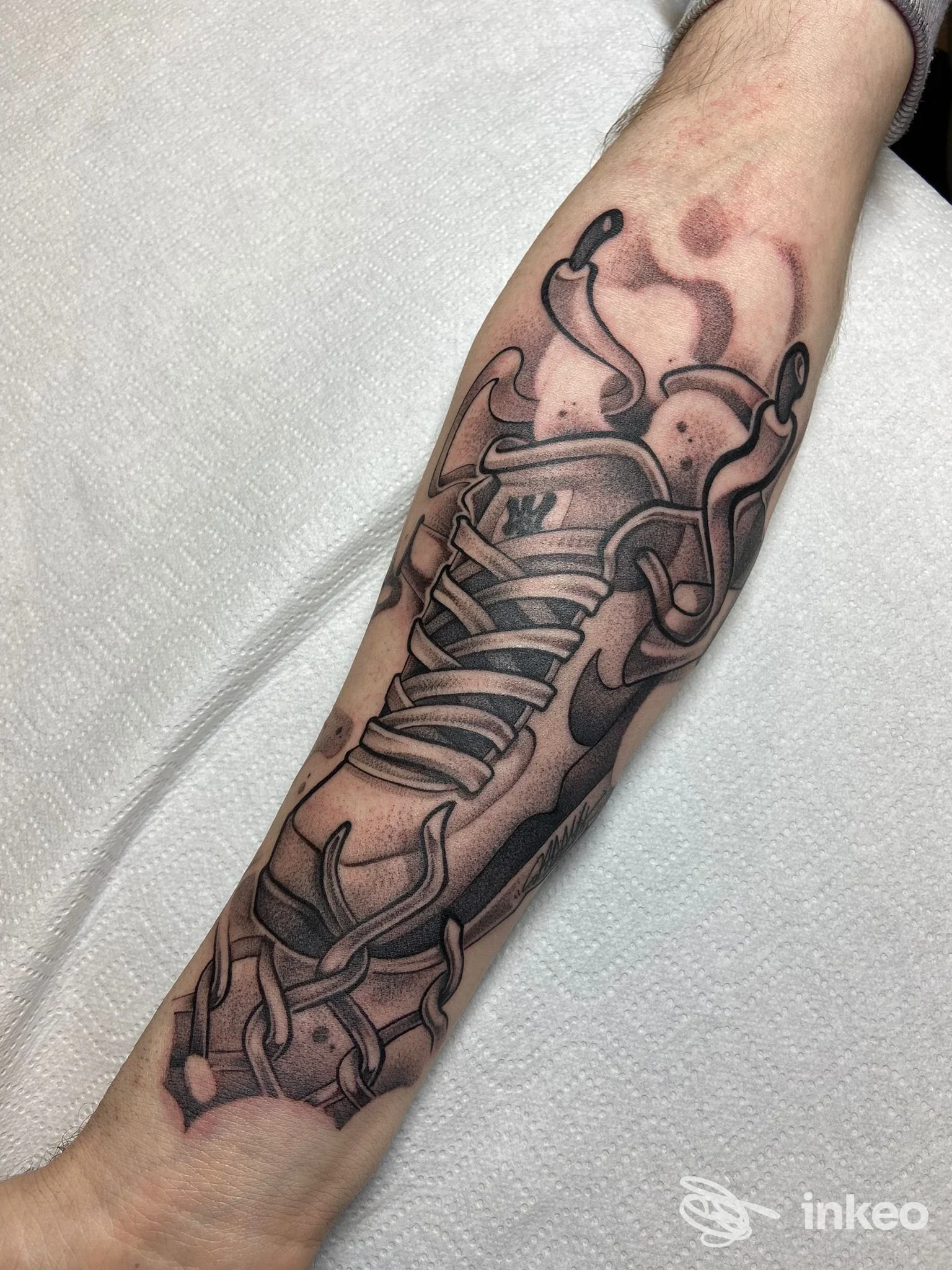 Tattoo visibile su avambraccio raffigurante una sneaker stilizzata in tonalità scure, realizzata dal Dont Cry Tattoo Collective a Napoli.