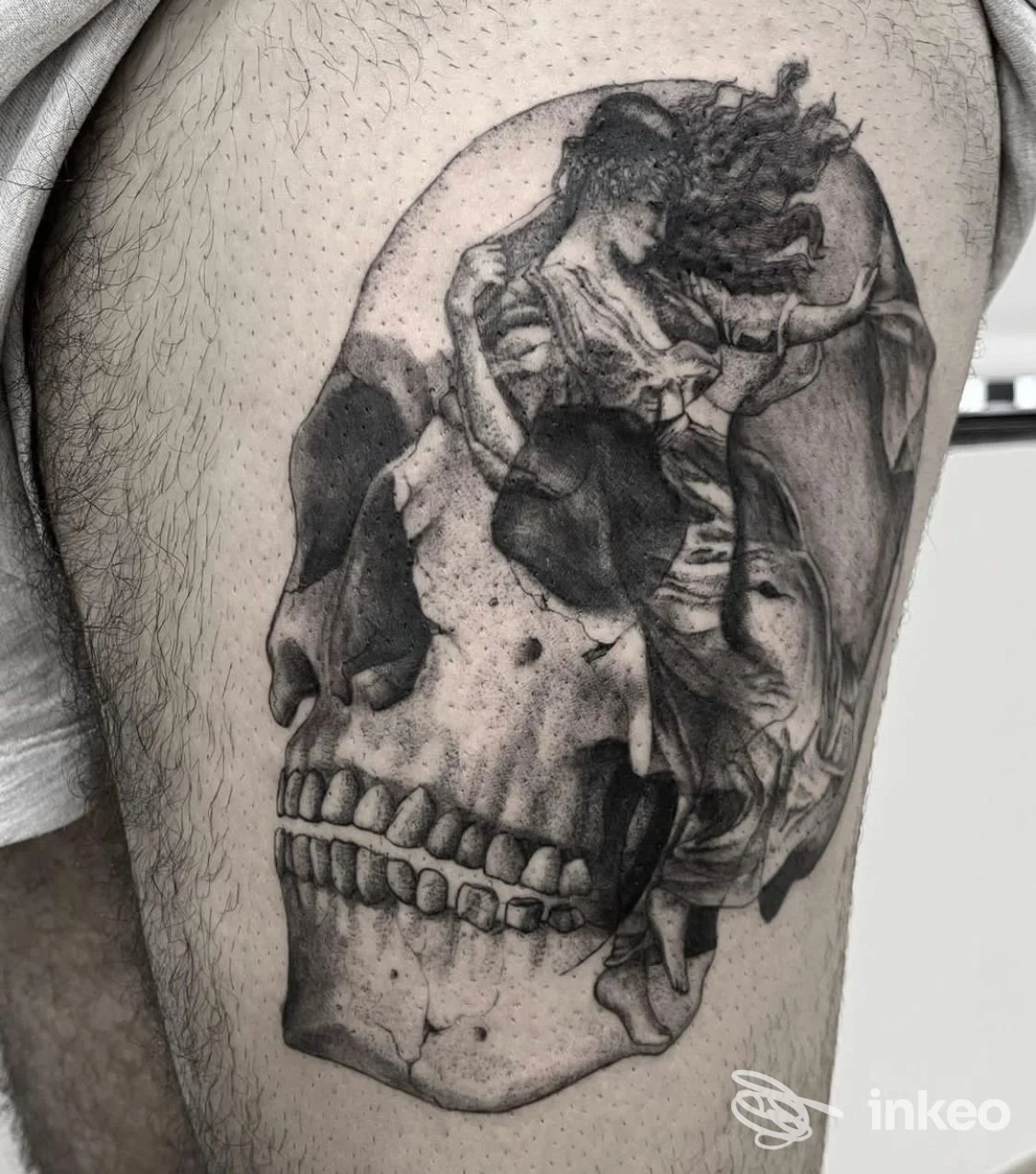 Tatuaggio realistico di teschio su pelle, con dettagli in tonalità nero/grigio e elementi astratti all'interno, visibile sulla parte superiore della gamba.