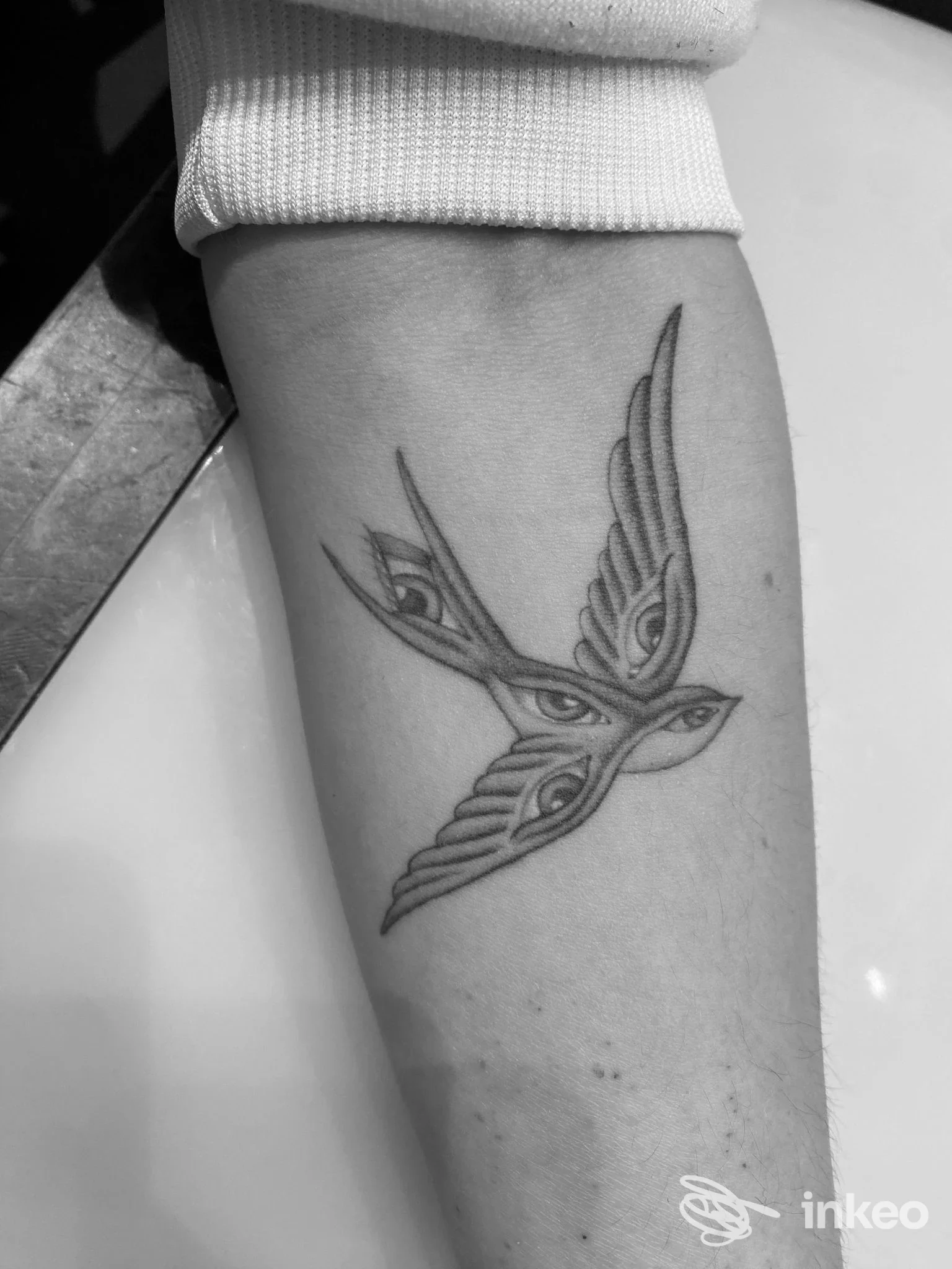 Avambraccio con tatuaggio stilizzato di due uccelli in volo, linee nette e dettagli leggeri.