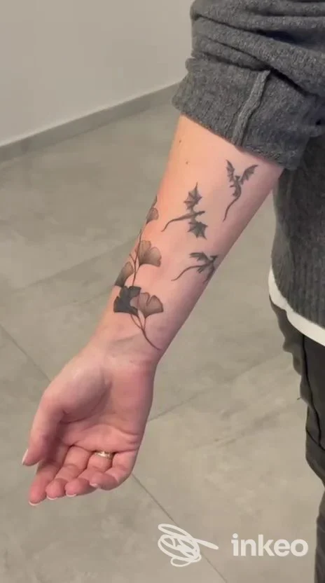 Tatuaggio visibile sull'avambraccio di una persona, realizzato presso Studio Levriero a Cologno Monzese, raffigurante rami e fiori.