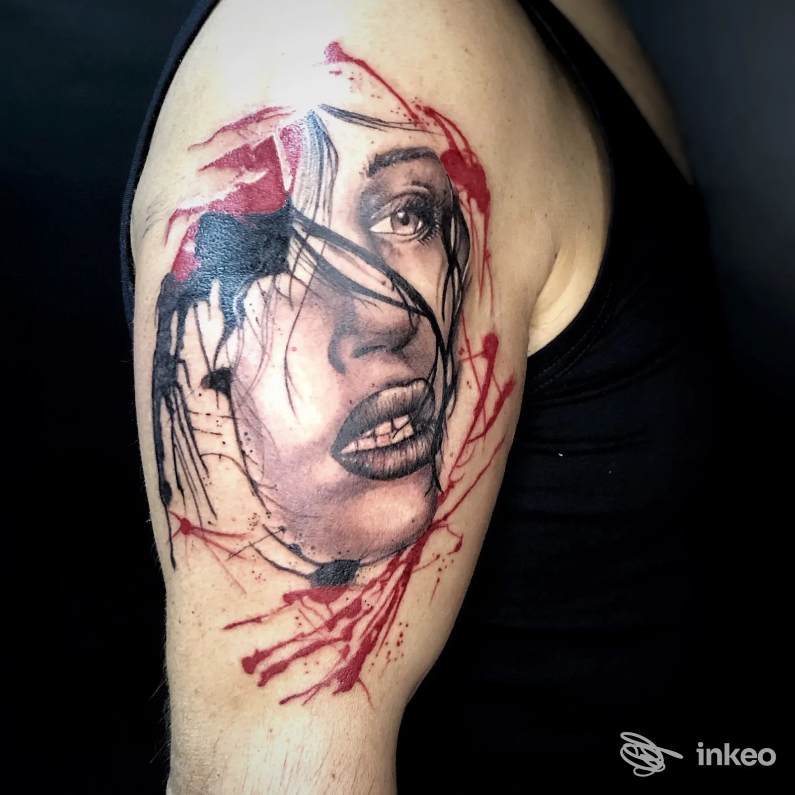 Tatuaggio realistico di una donna sul braccio: ritratto in bianco e nero con accenti rossi, dettaglio di nascite e linee ornamentali, su pelle reale.