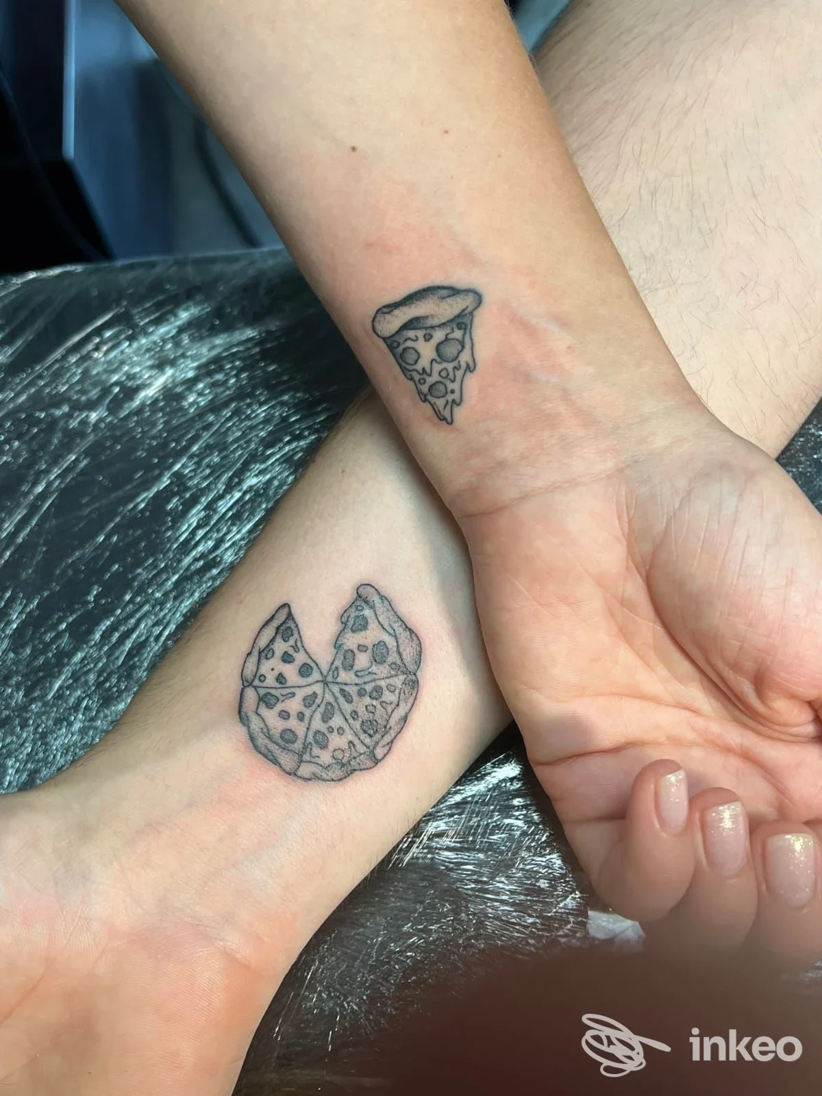 Due piccoli tatuaggi a pizza visibili sul polso e sull’avambraccio, realizzati sulla pelle, senza elementi di interfaccia sociale o immagini sovrapposte.