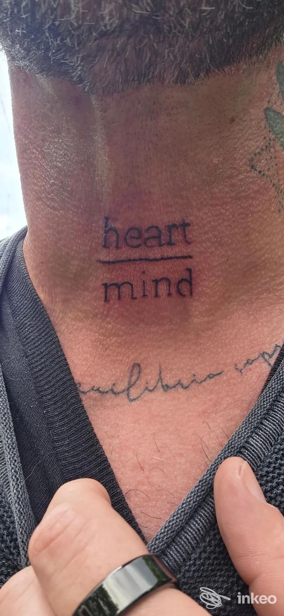 Tattoo sul collo visibile: scritta 'heart mind' in nero con sottolineatura, realizzato su pelle; visibile area del collo e parte della canotta, attribuito a InsideskinTattoo, Seriate.