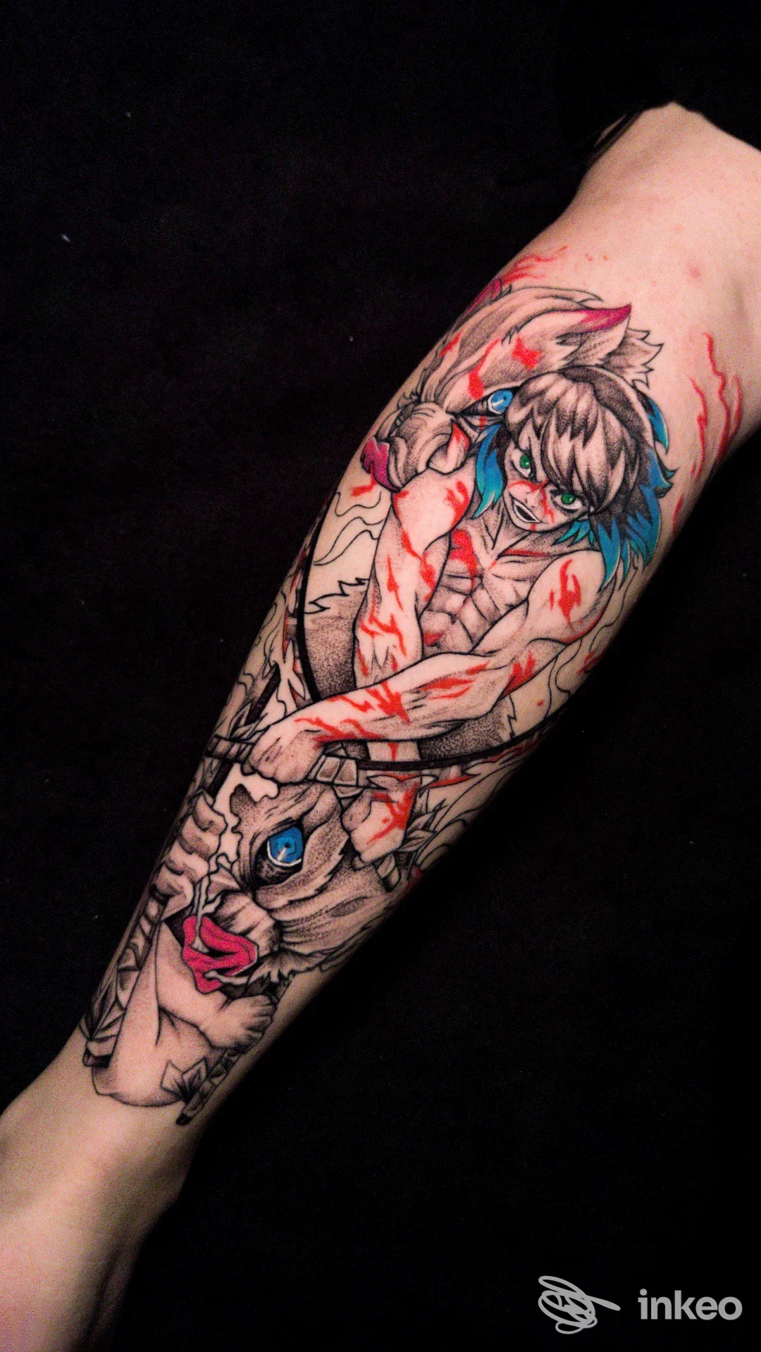 Tatuaggio a tema anime sull’avambraccio, linee scure e colori rosso e azzurro, raffigurante figura umana disegnata sulla pelle.