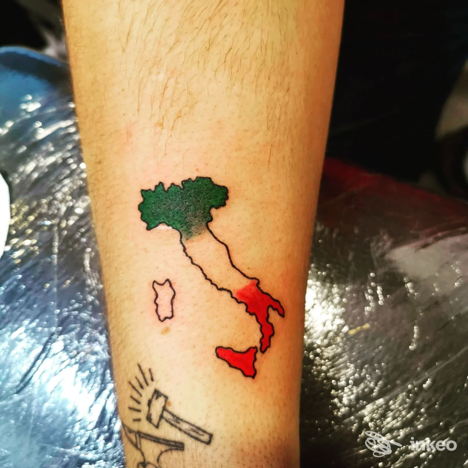 Tattoo sull'avambraccio raffigurante l'Italia: una mappa colorata con parti verdi, bianche e rosse, realizzata sulla pelle.