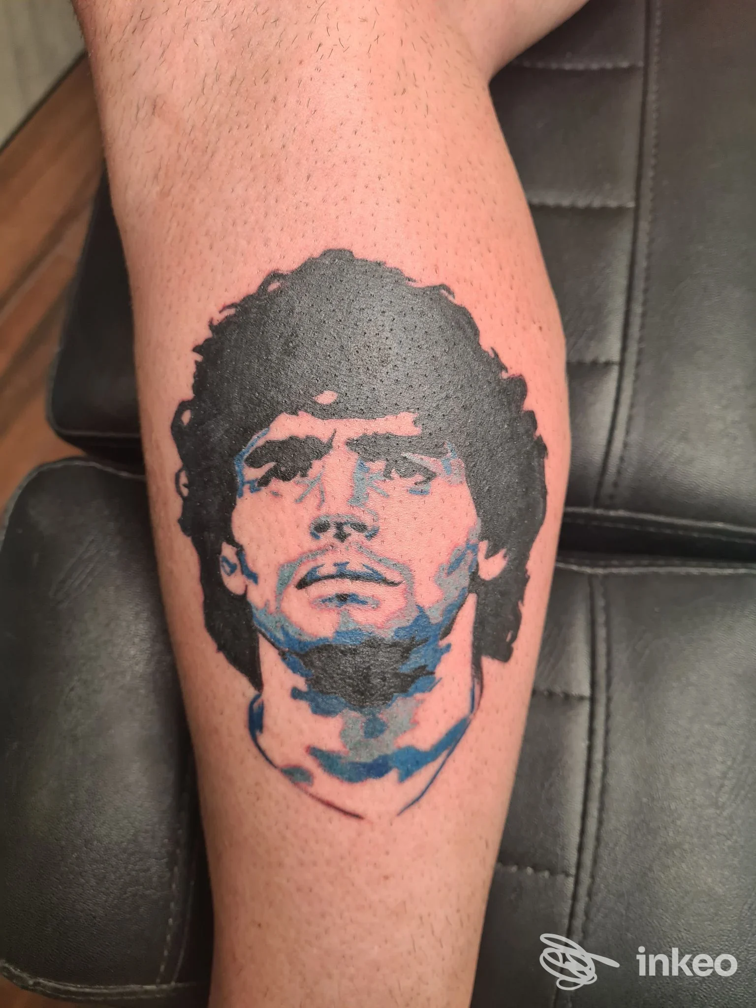 Tattoo ritratto stilizzato in bianco e nero e blu su avambraccio, raffigurante un volto umano con tratti marcati e ombre artistiche. studio DG Ink nel CastVolturno.
