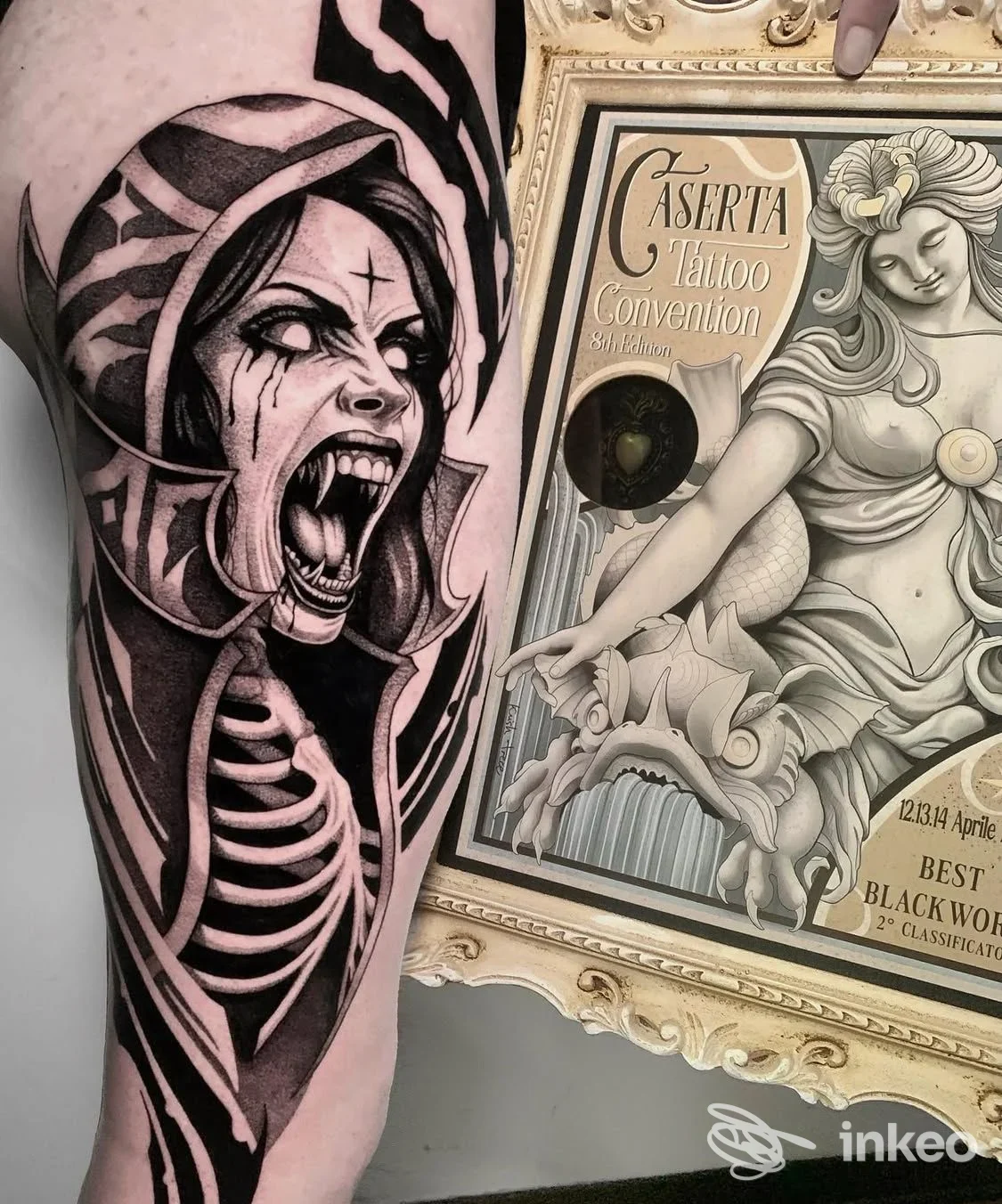 Tatuaggio in stile blackwork su una superficie della pelle, raffigurante una creatura agguerrita con la bocca aperta, animale/cartooned horror, sul braccio vicino a cornice decorativa. Nessun volto umano intero visibile.